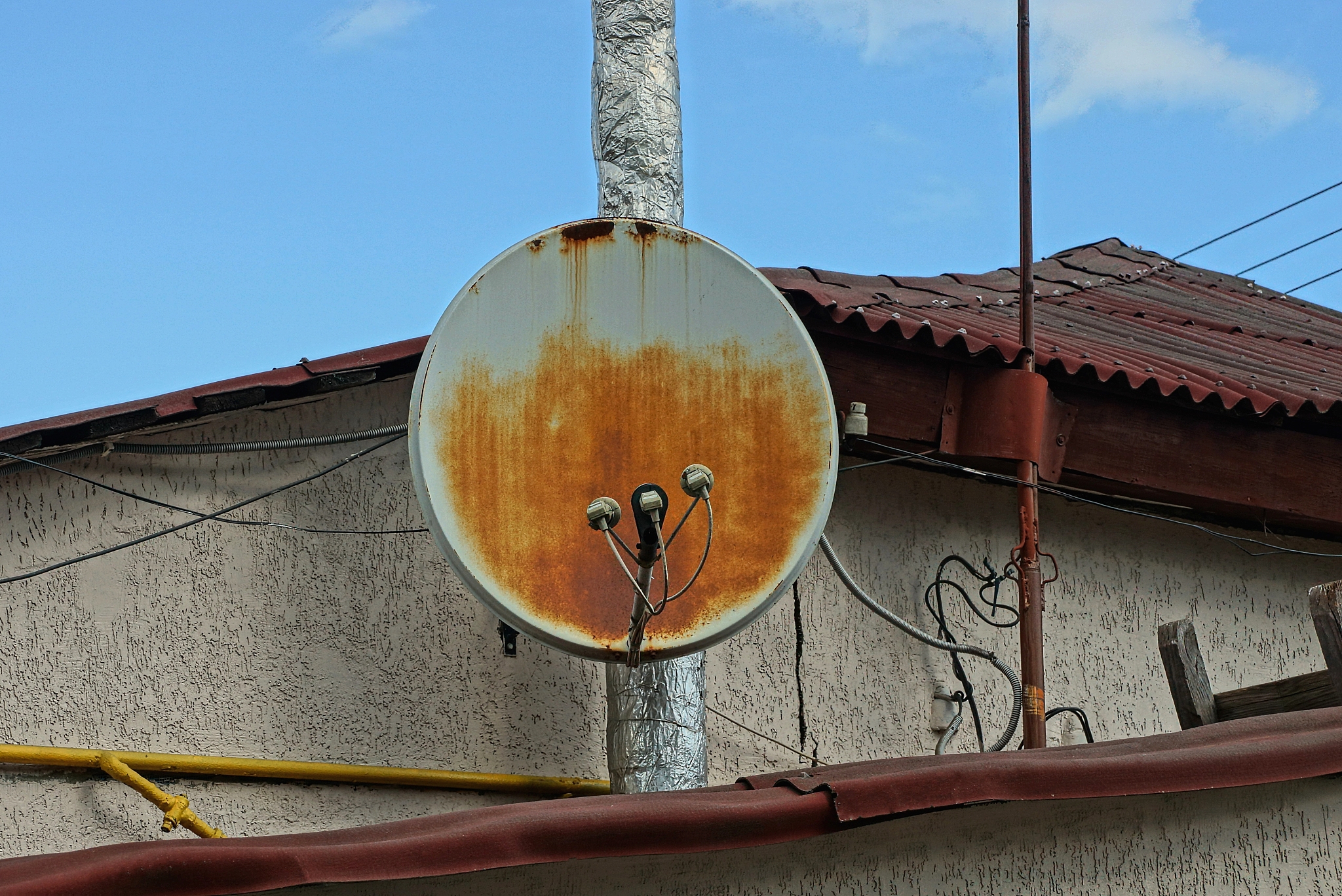 one old rusty satellite dish on the wall of a house
