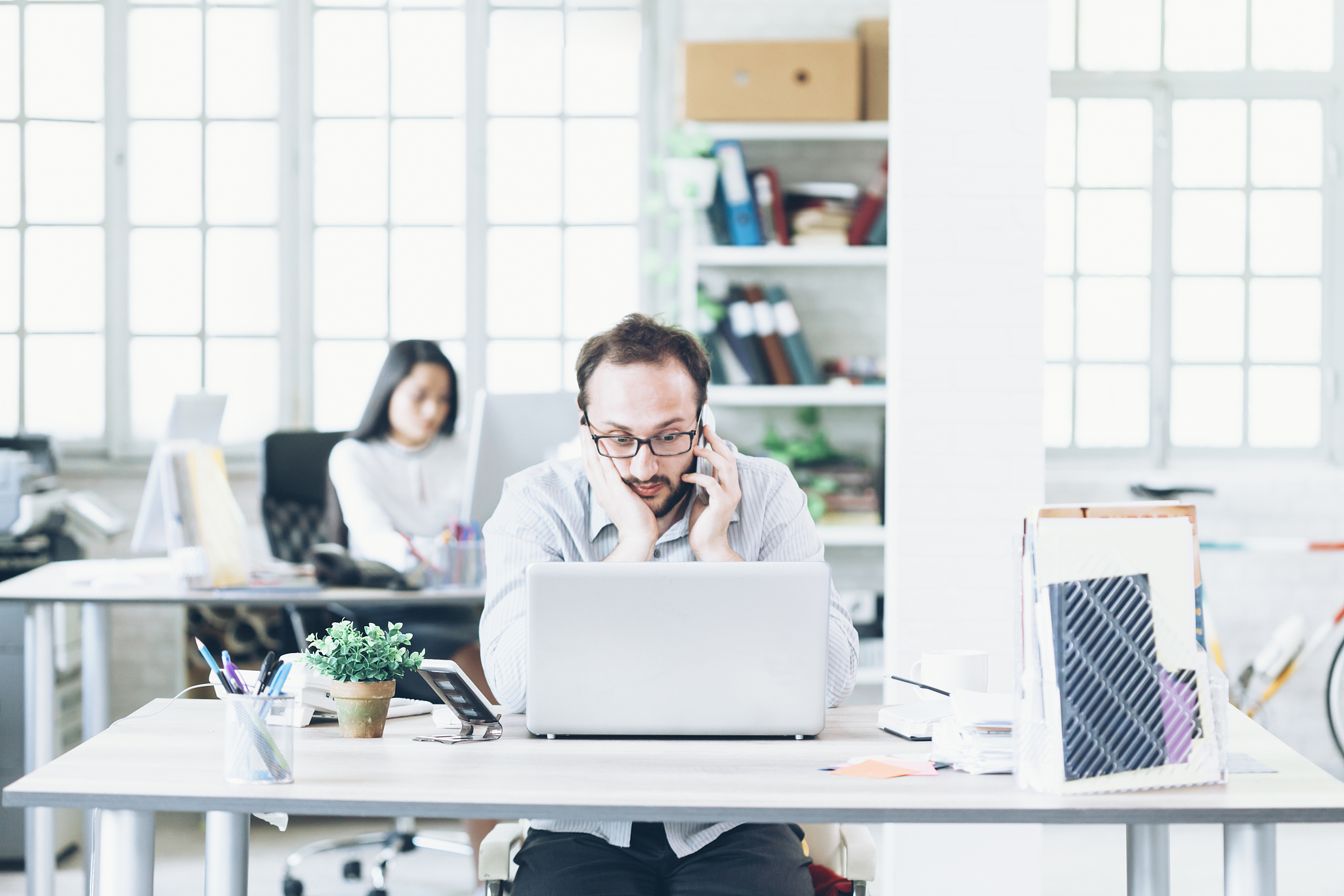 worried young man talking on smart phone at work