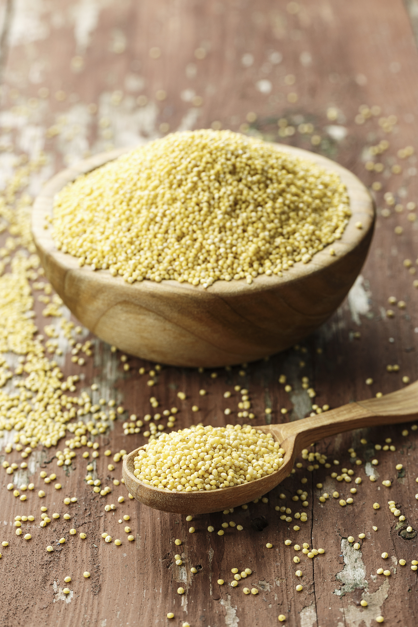 raw millet groats in a wooden plate on a shabby wooden backgroun