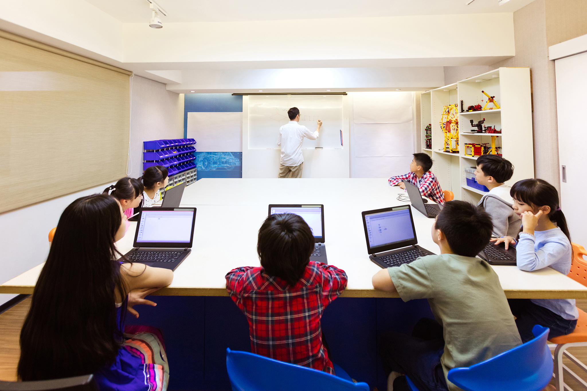 teacher explaining students using laptops in school