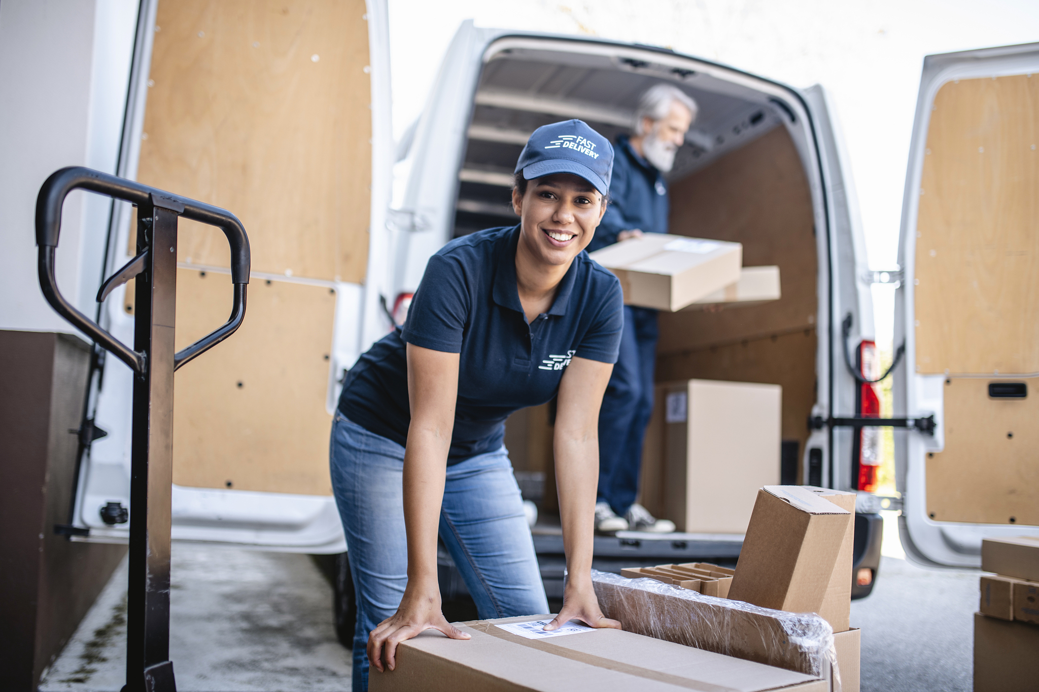 uniformed female gig delivery worker loading parcels on van