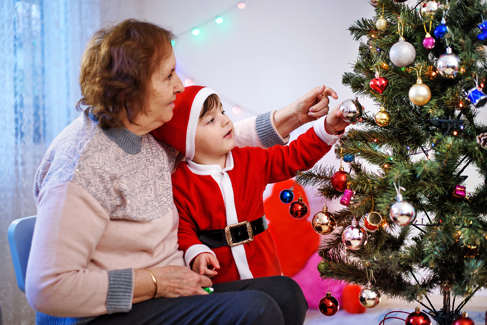 grandmother and grandson decorating a christmas tree