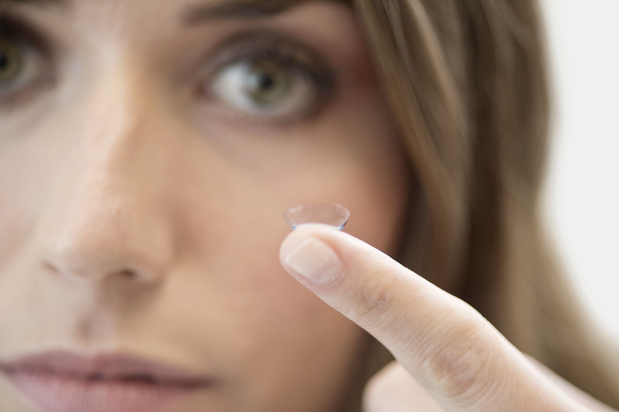mid adult woman with contact lens on finger