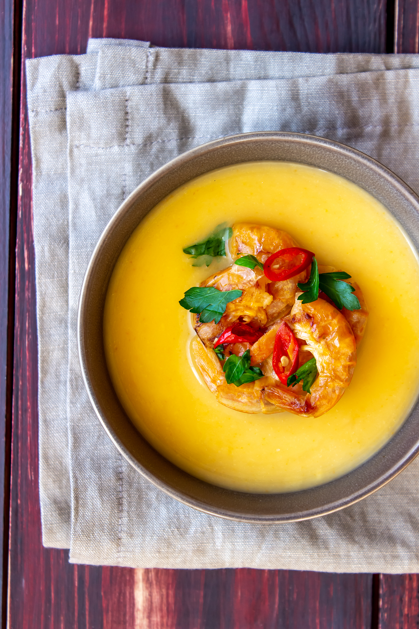 cheese cream soup with grilled shrimp on a wooden background.