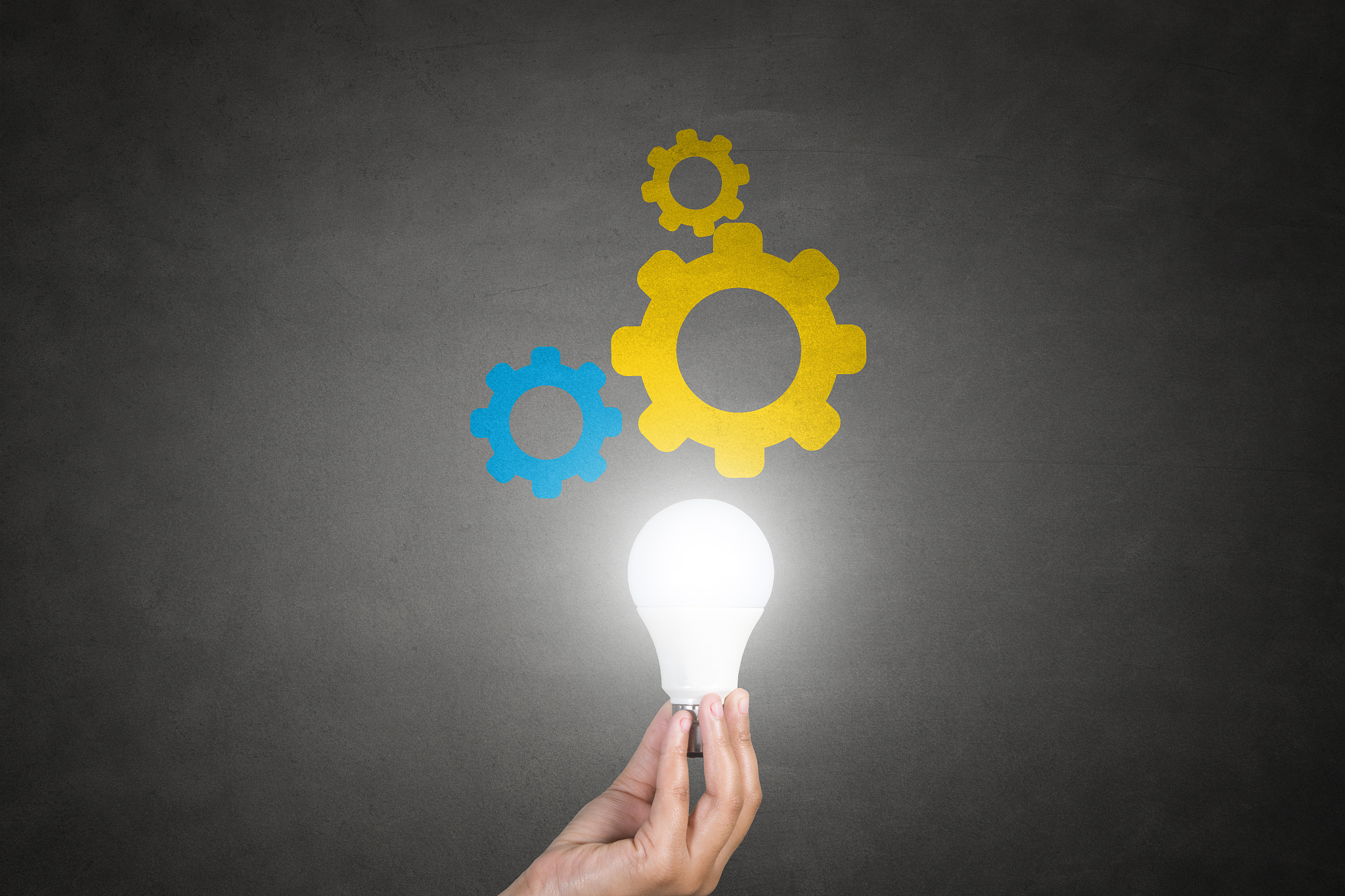 human hand holding light bulb with gears