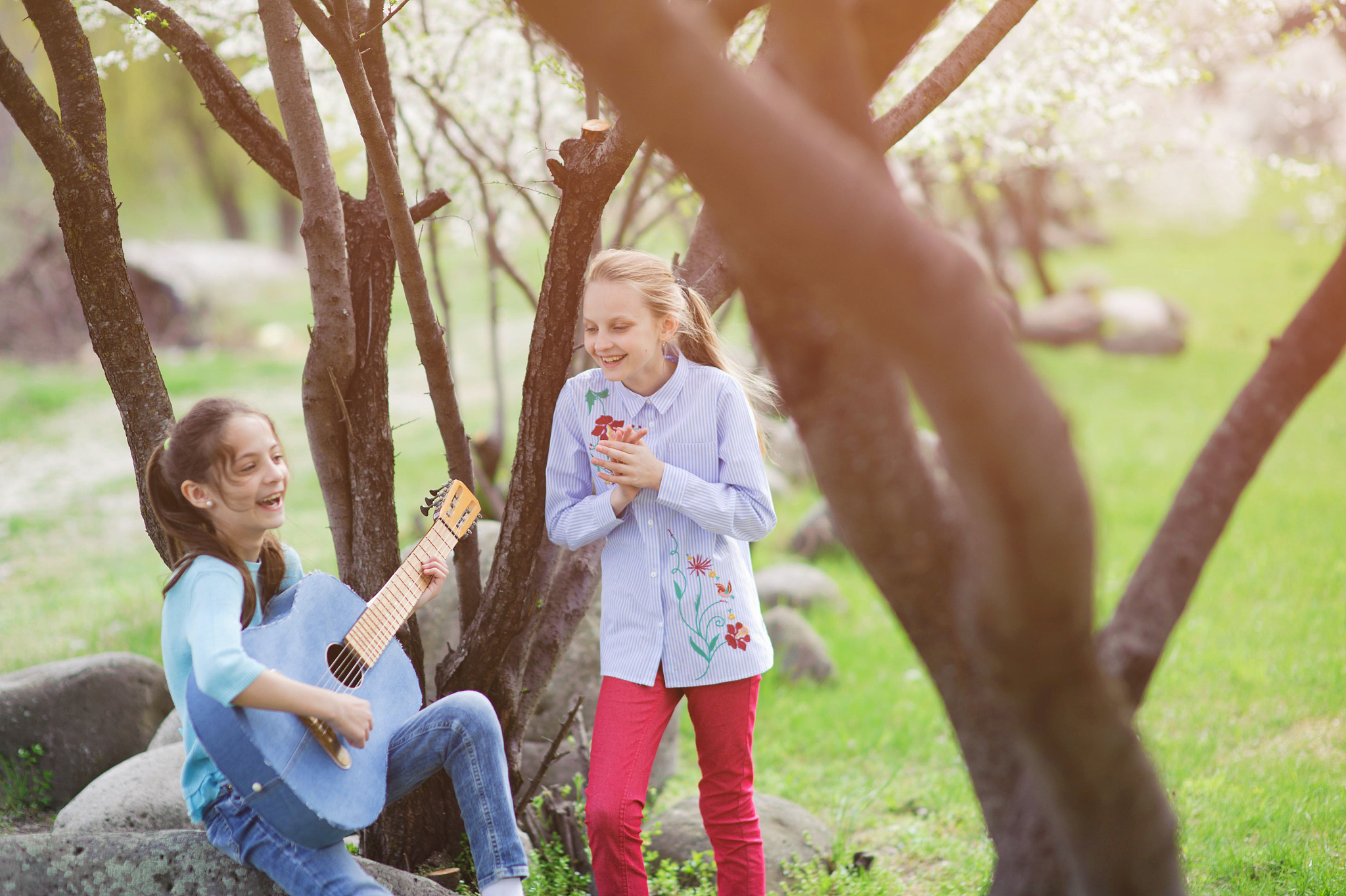 two happy beautiful caucasian laughing little girls playing guit