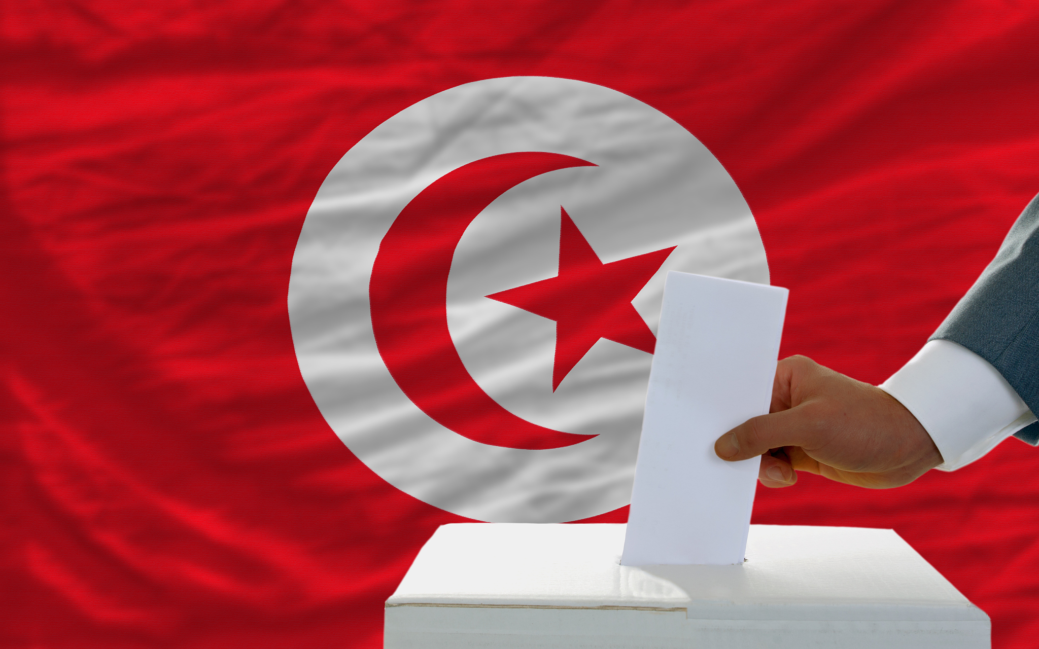 man voting on elections in tunisia front of flag