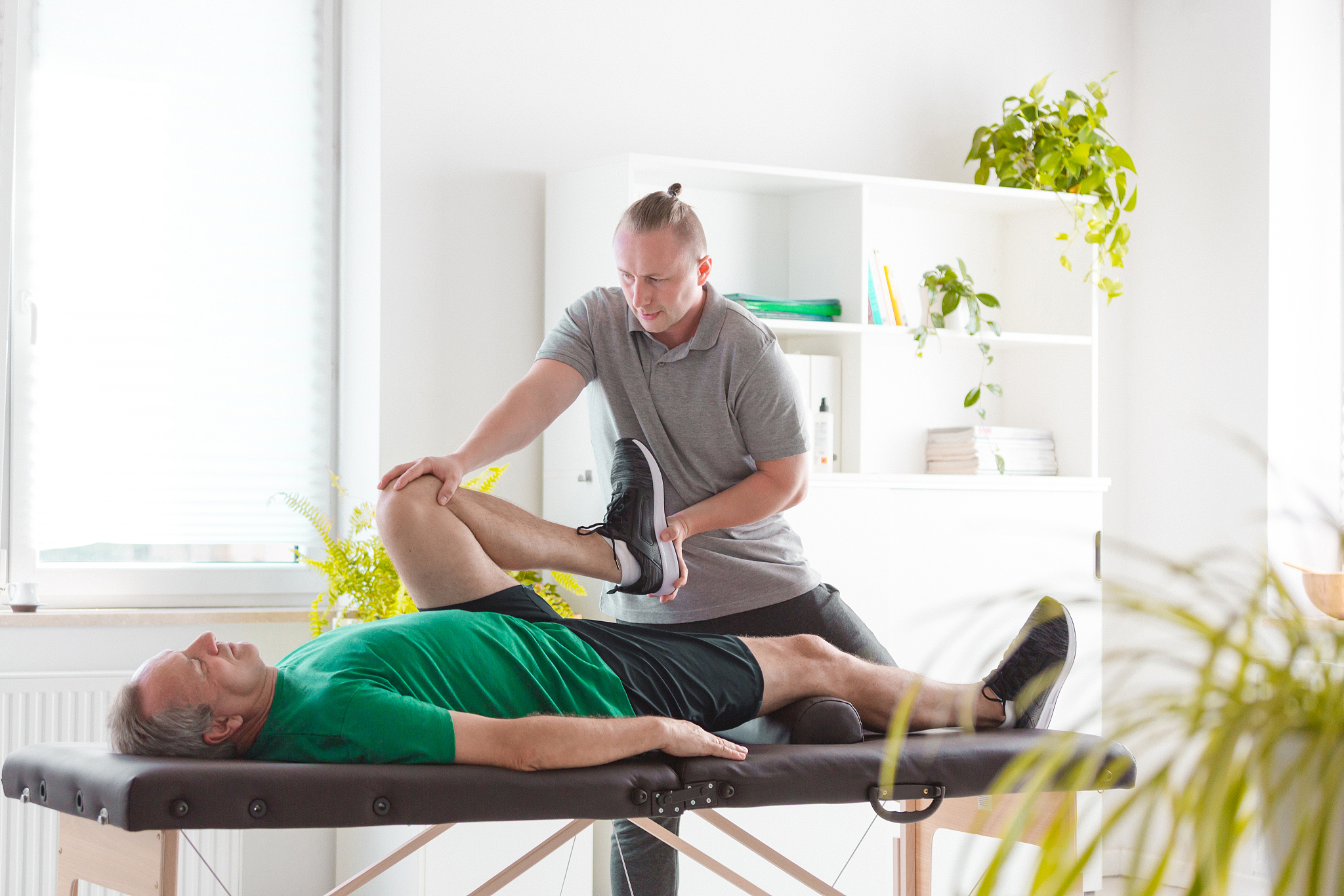 physiotherapist stretching man's legs