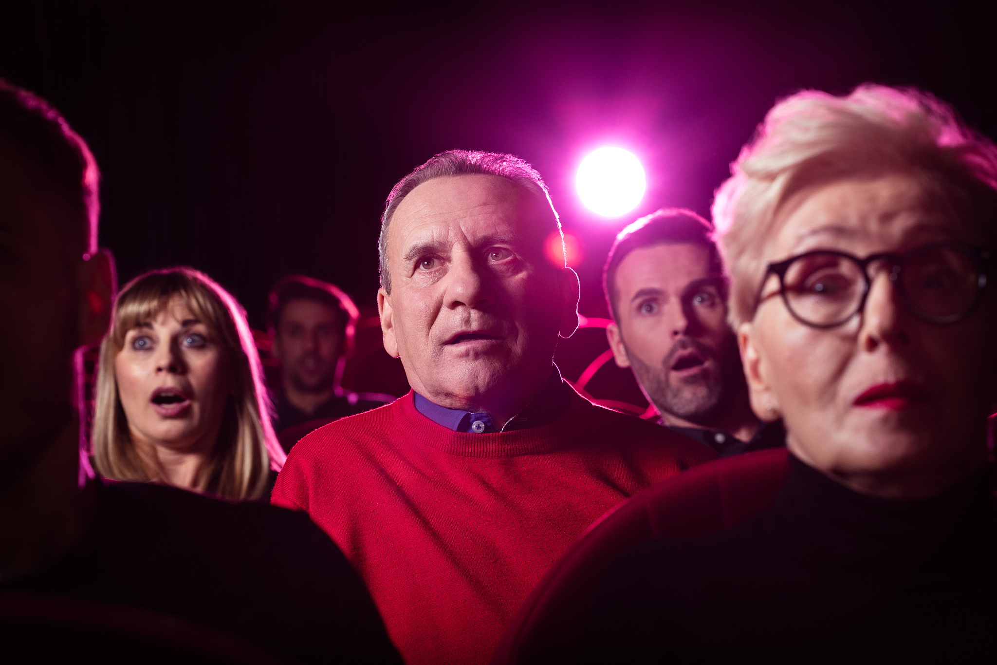 senior man watching an interesting movie at the cinema