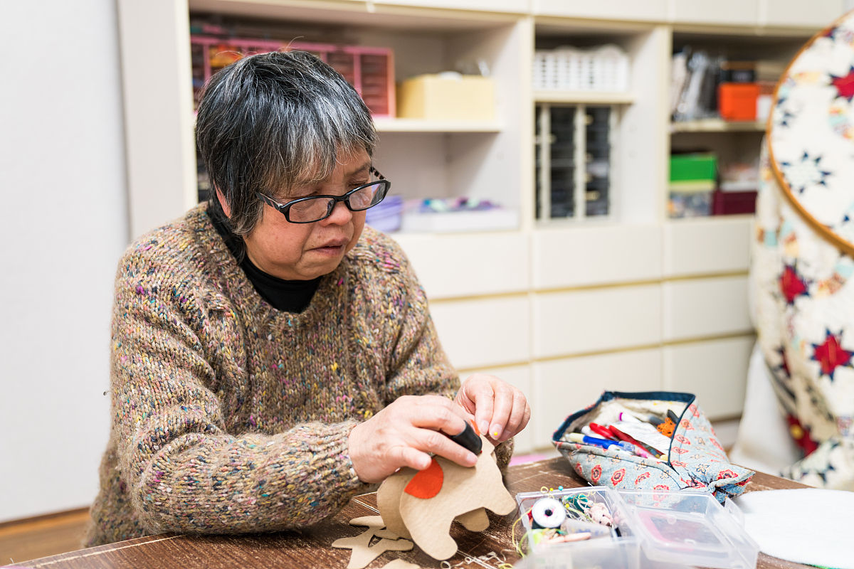 一位年长妇女在她的家中缝纫和制作工艺品