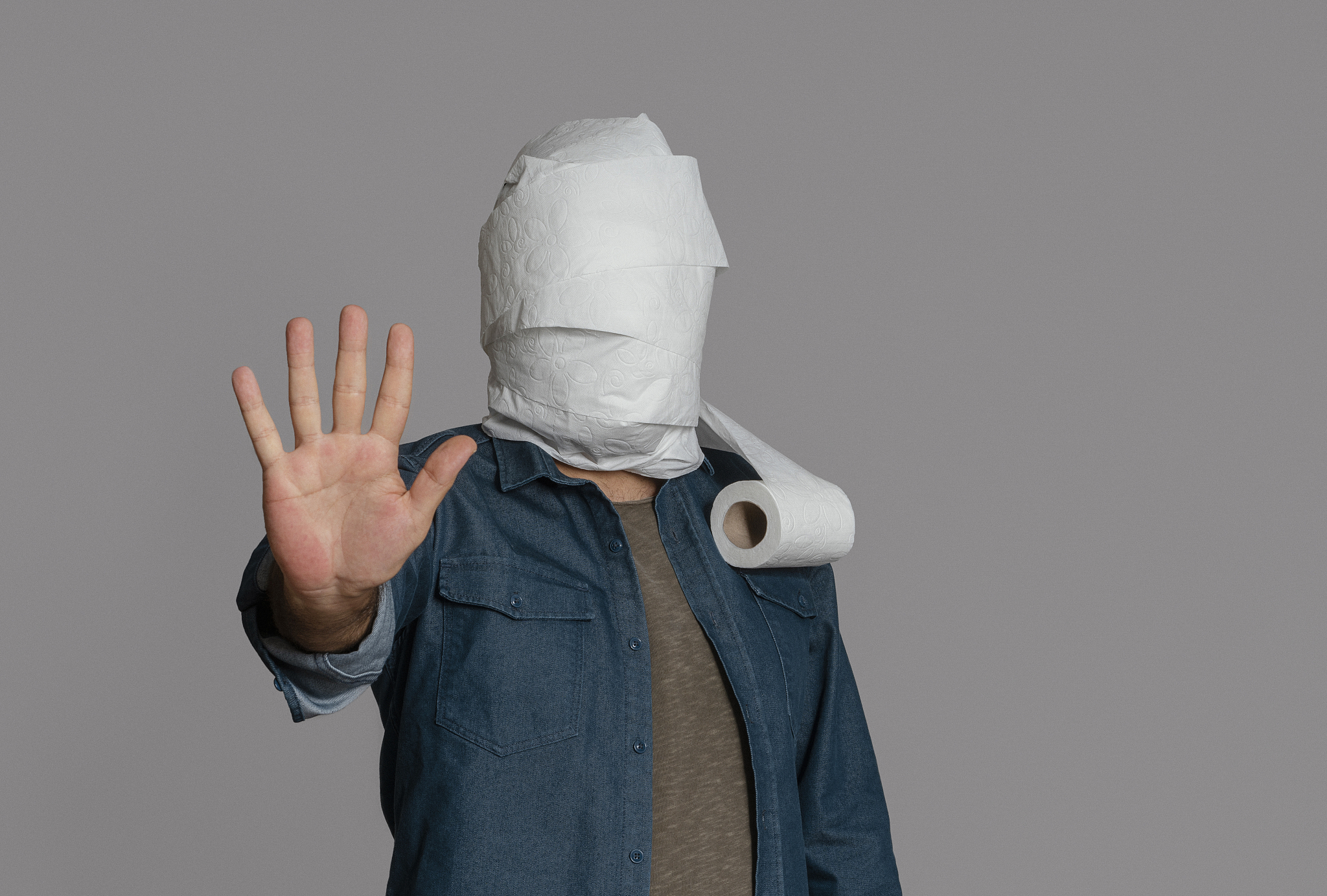 man raising hand gesturing stop sign, his head covered with with