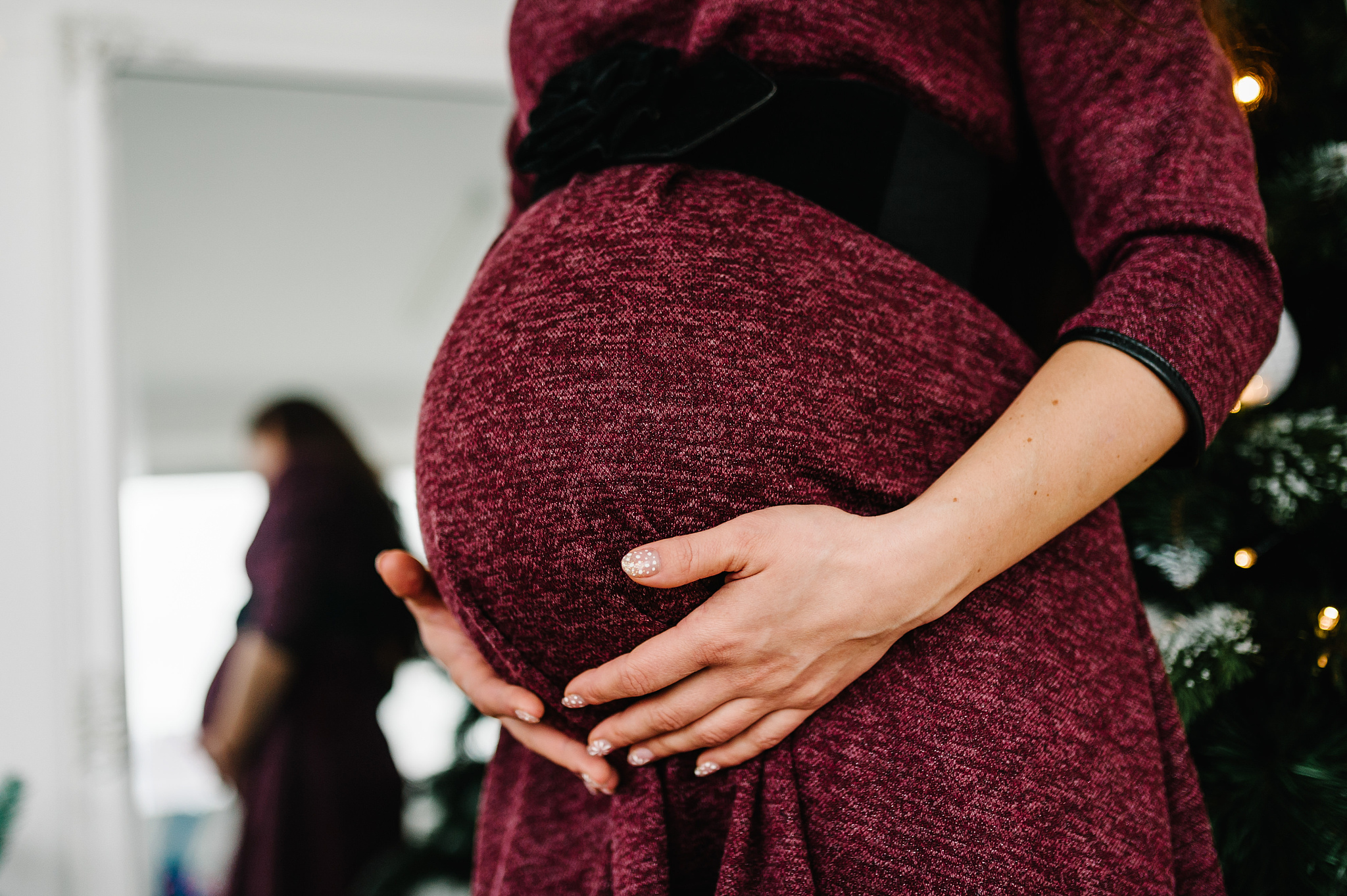 cropped photo of pregnant woman in a red dress stands near the c