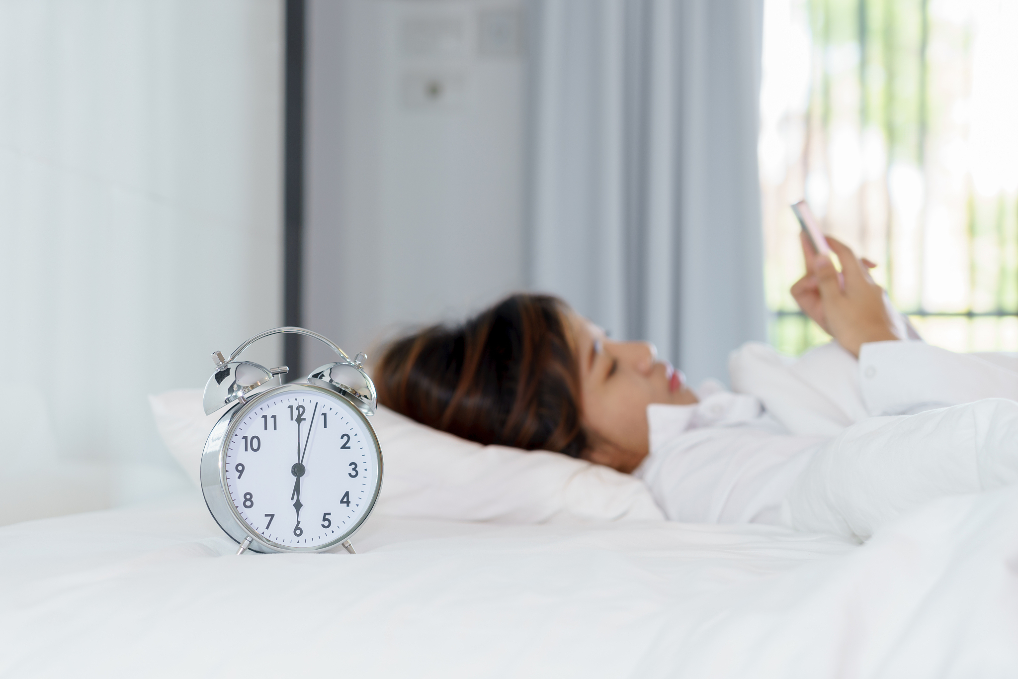 young woman using smart phone on bed when waking up in the morni