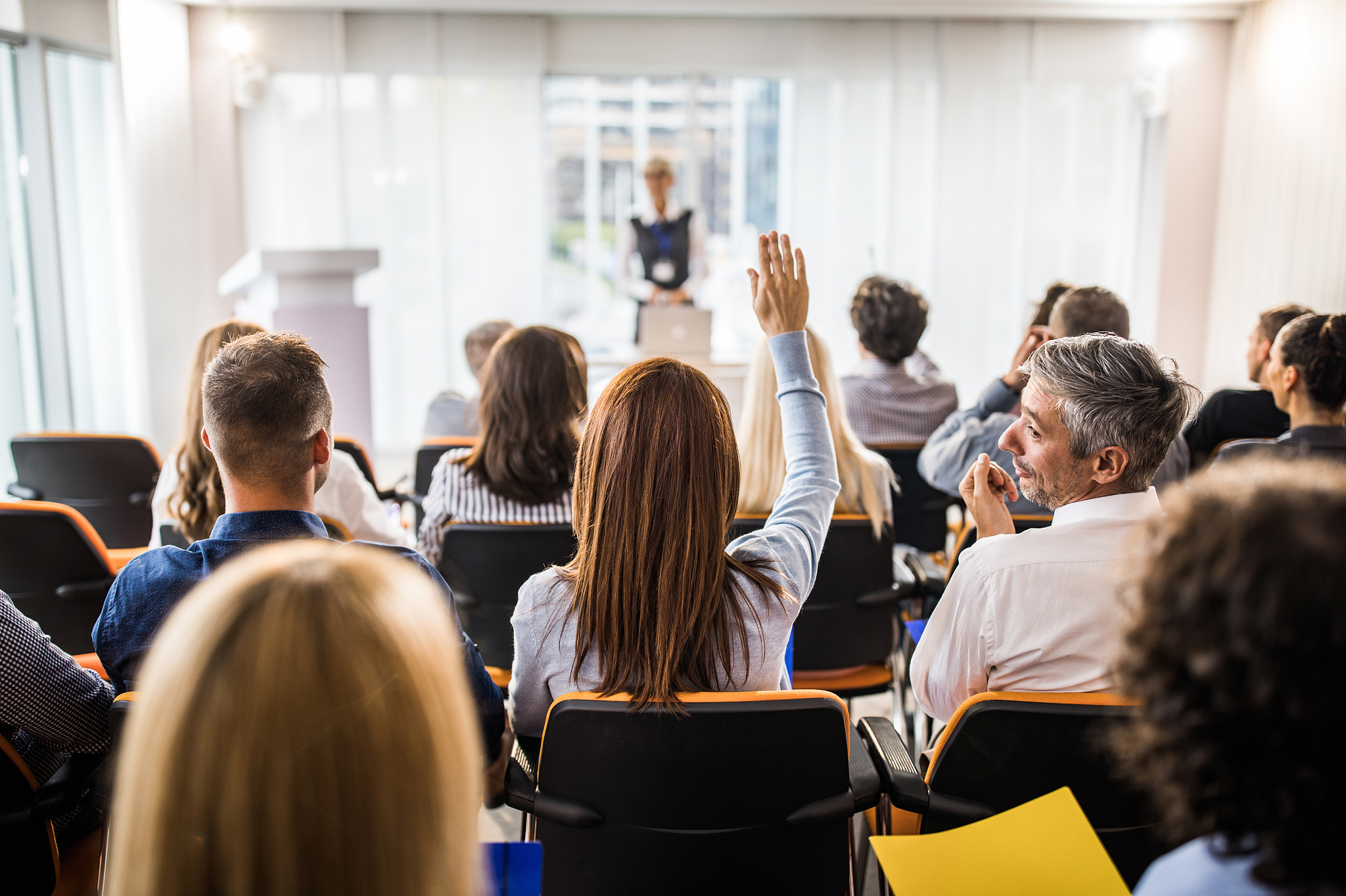 back view of a businesswoman raising her hand on a seminar in bo