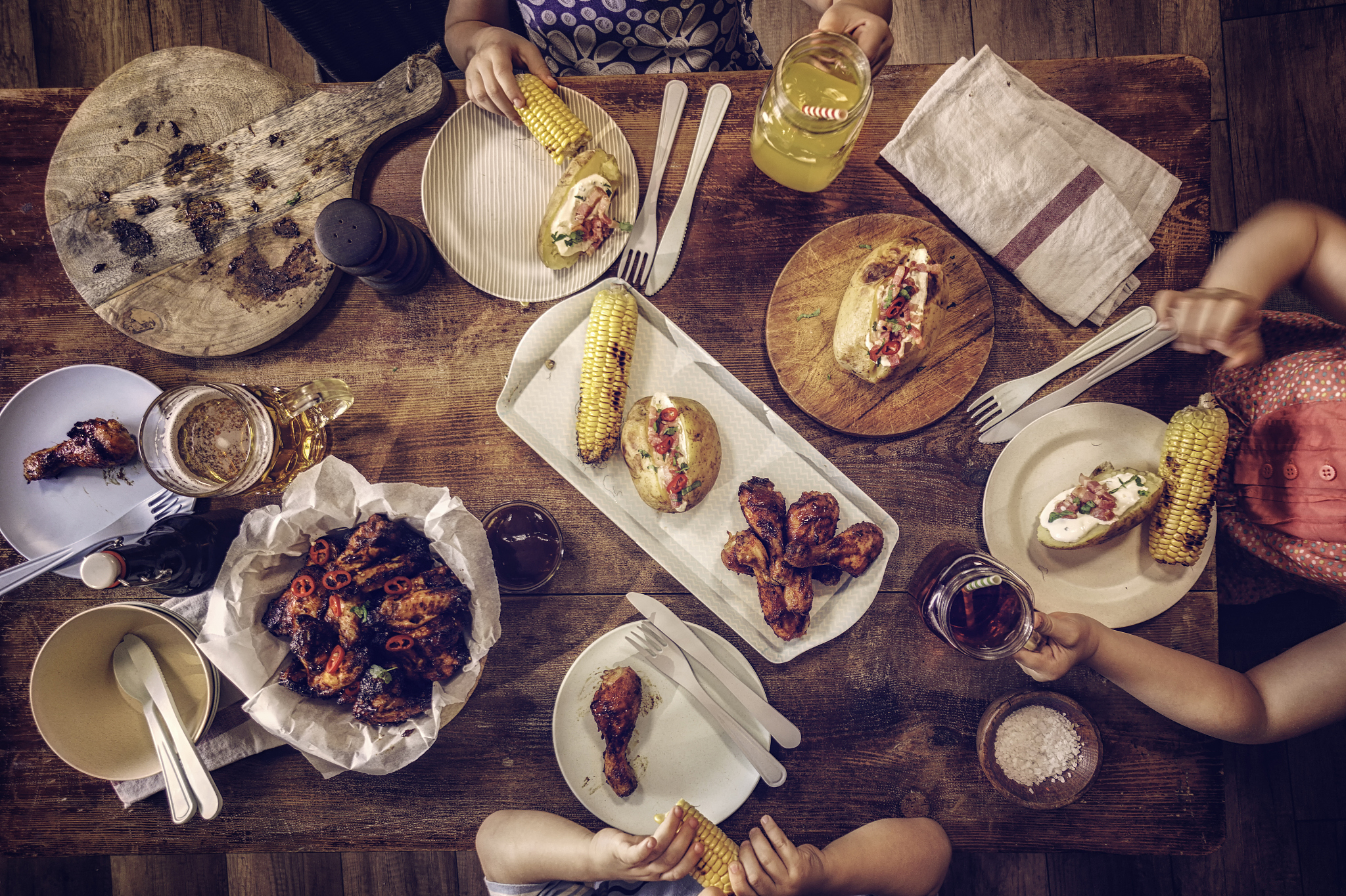 eating spicy chicken wings with baked potato and corn