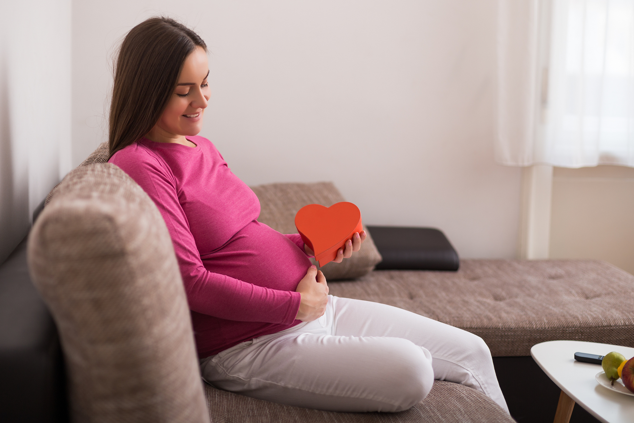 pregnant woman pregnant  holding red heart shape