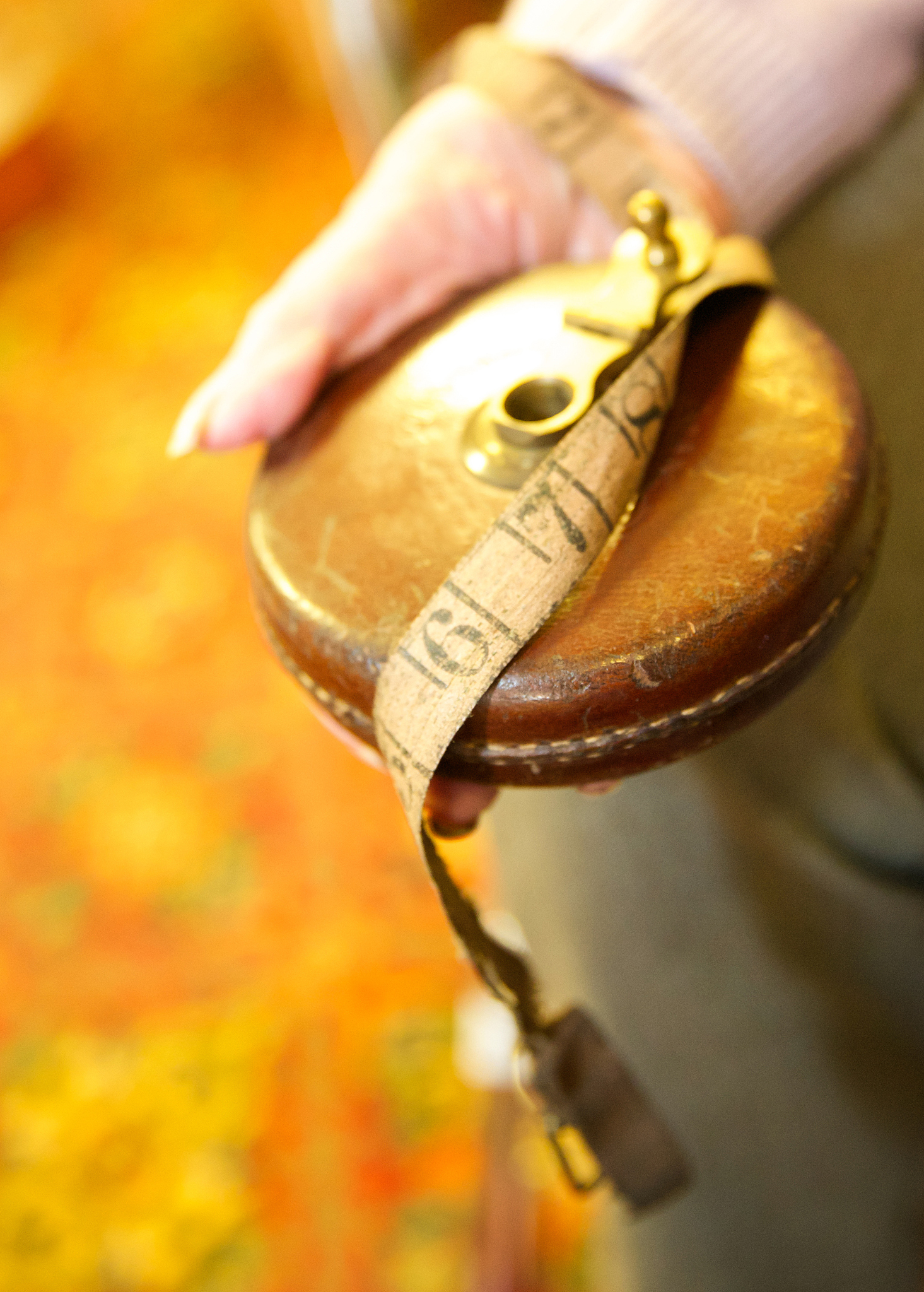 elderly hand holding an old leather imperial extendable tape mea