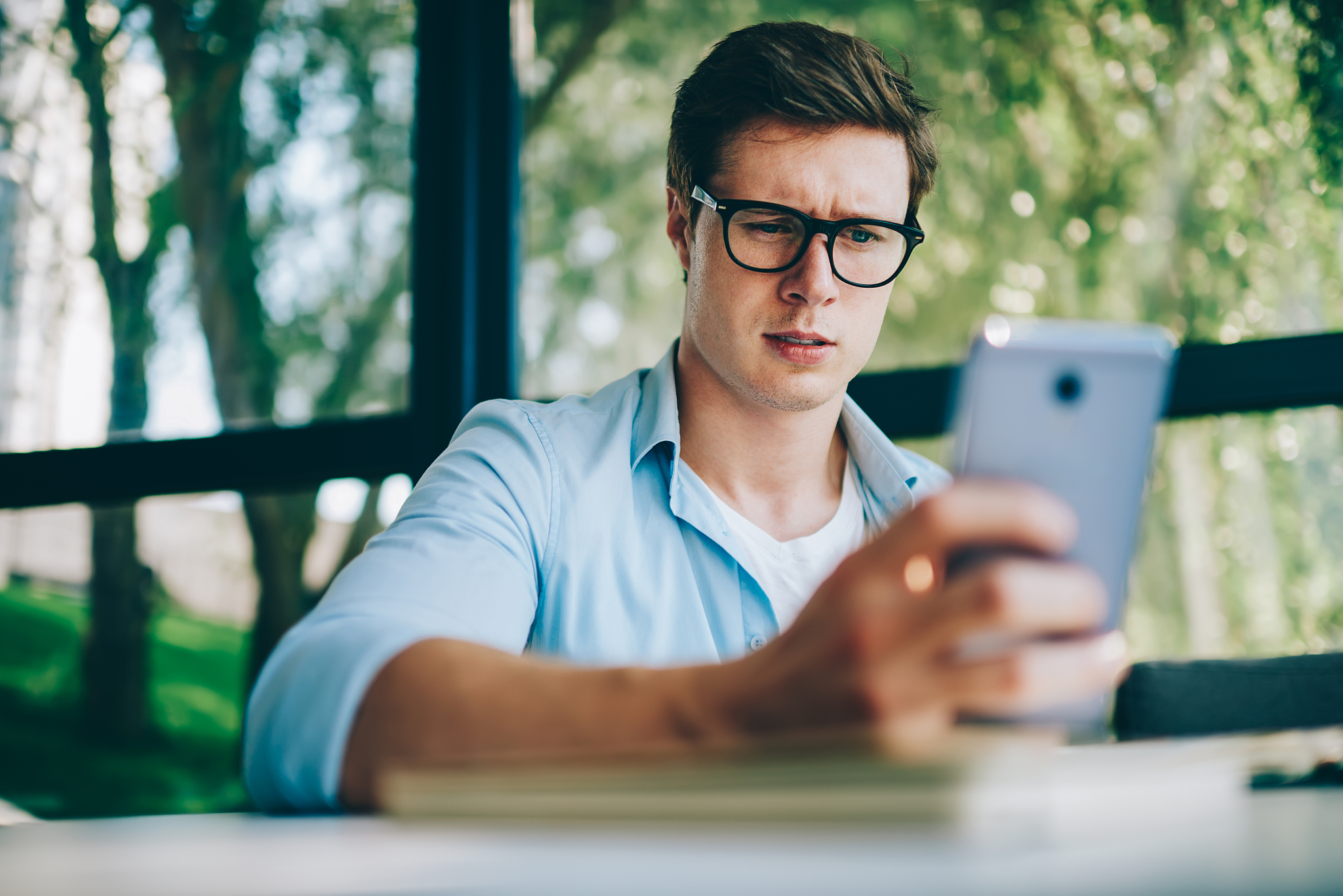 uncertain young man in eyeglasses reading incoming questioning n