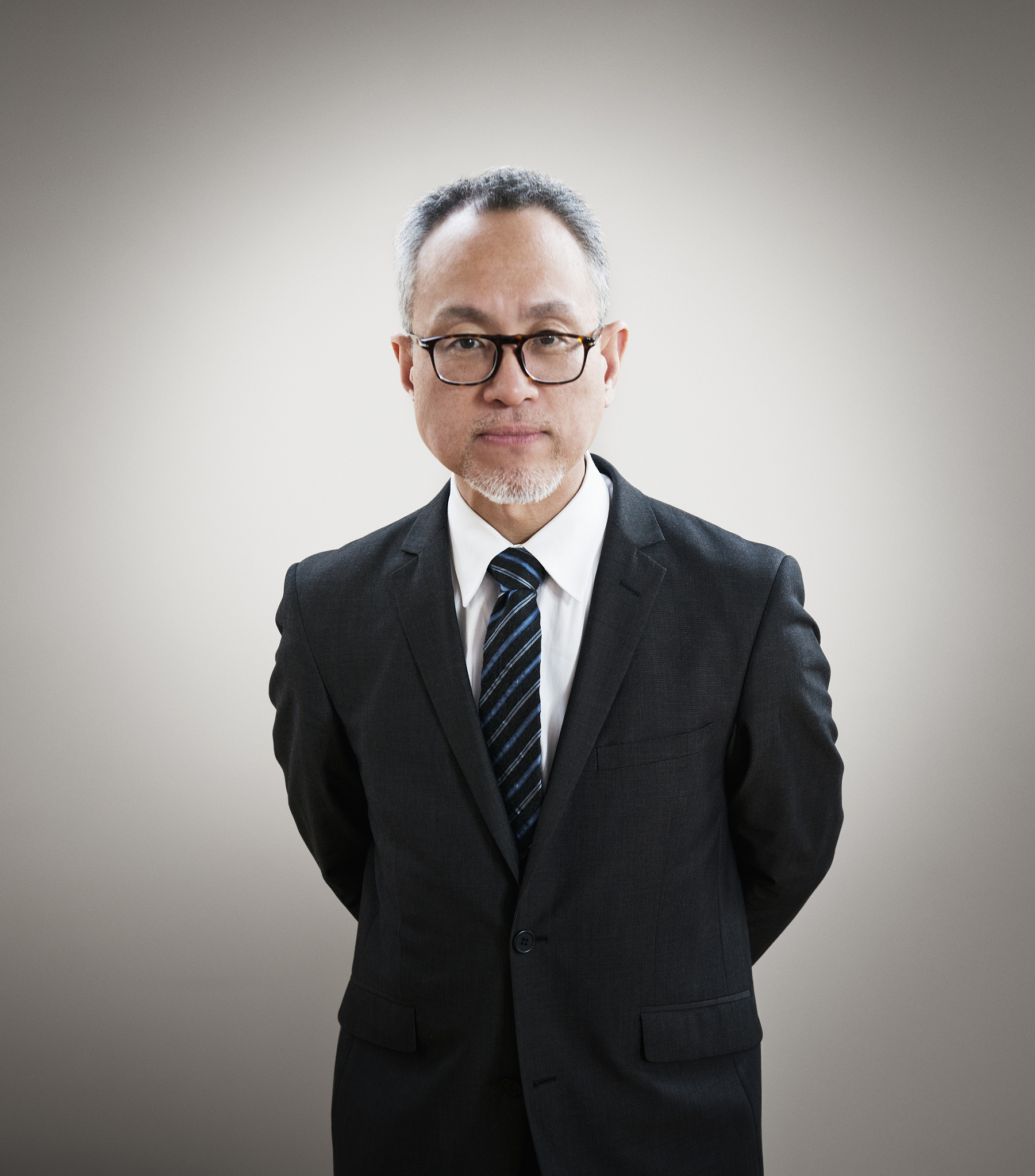 asian businessman standing with hands behind back