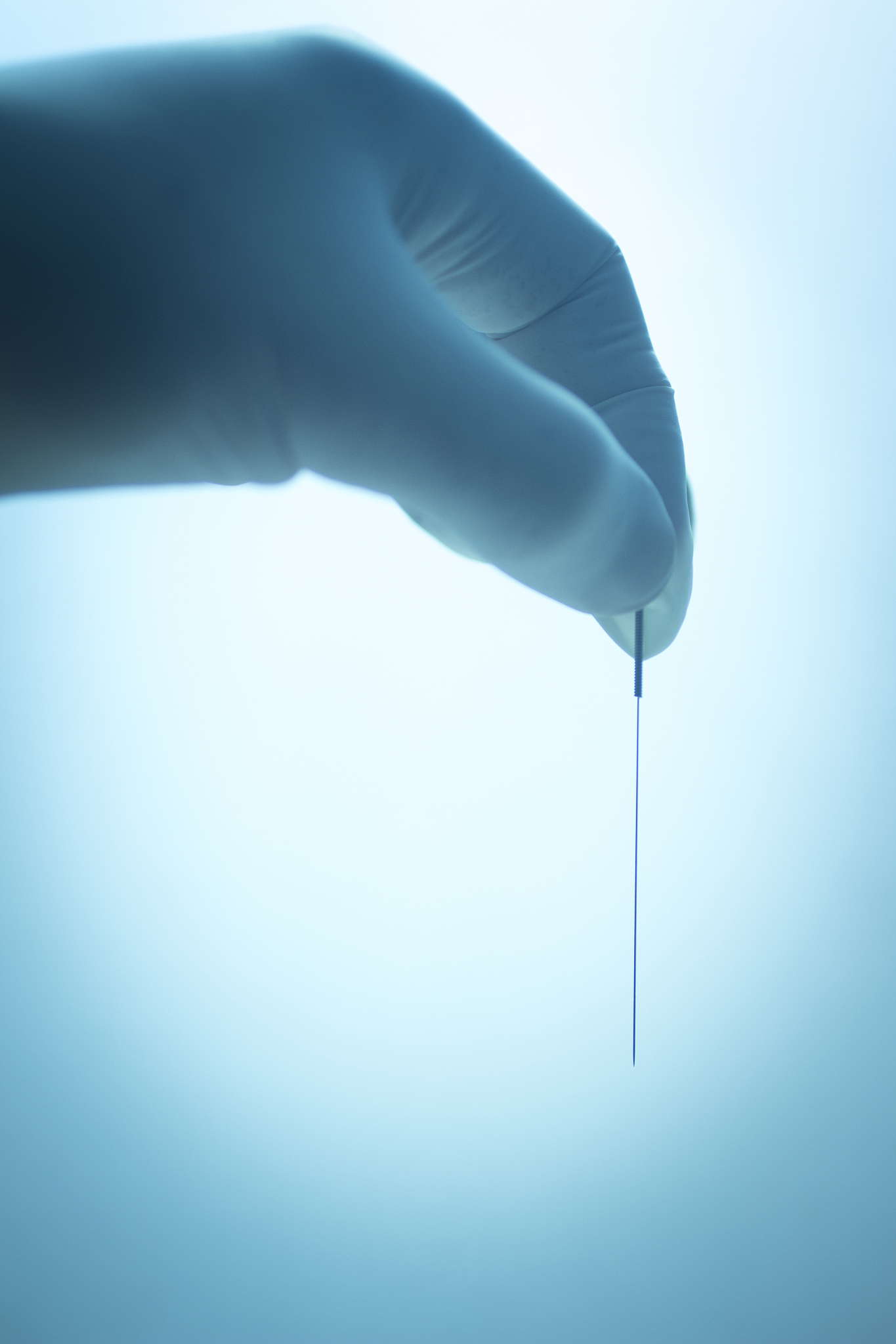 cropped hand holding acupuncture needle in hospital