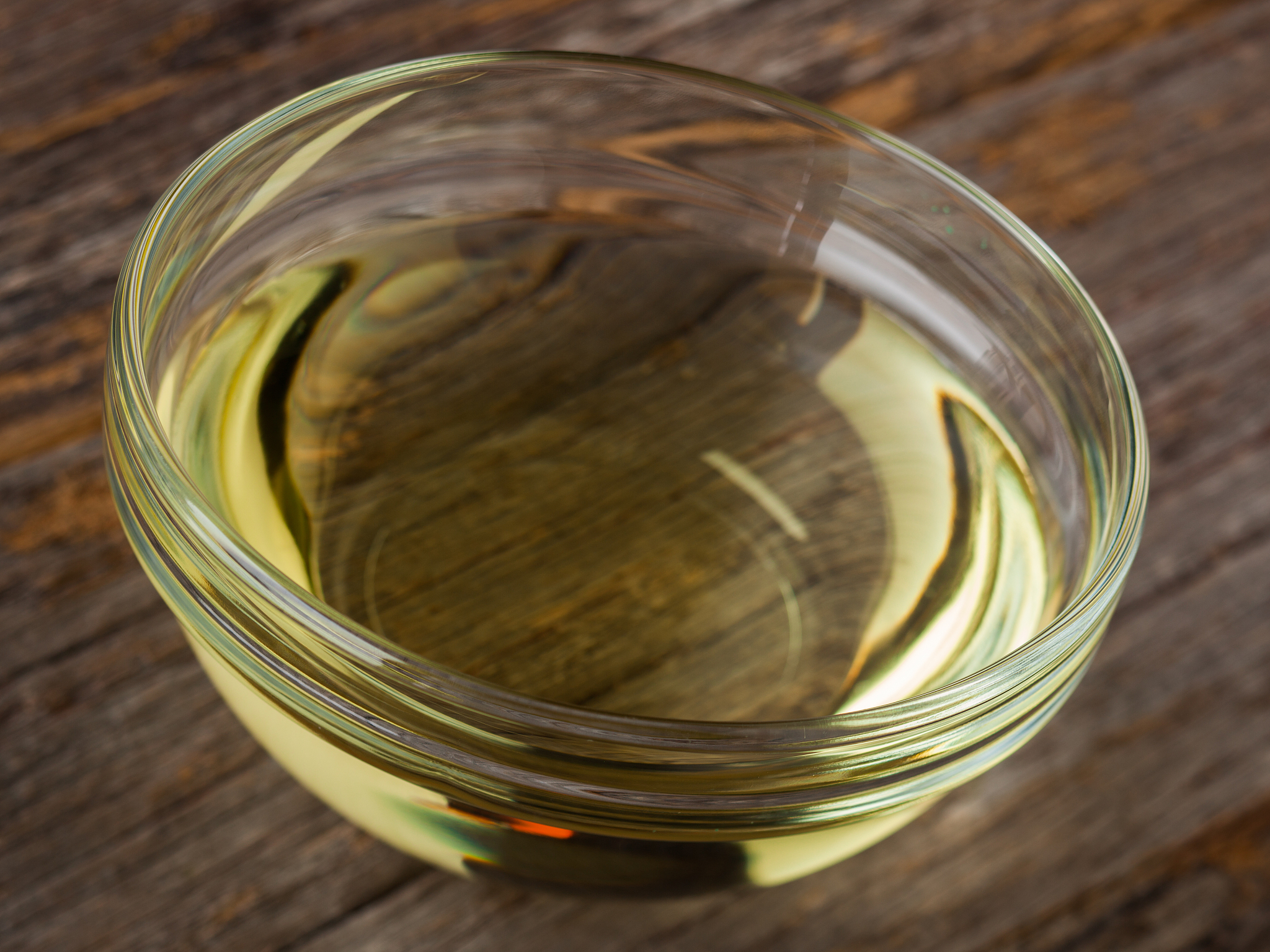 glass bowl of vegetable oil on rustic wood surface