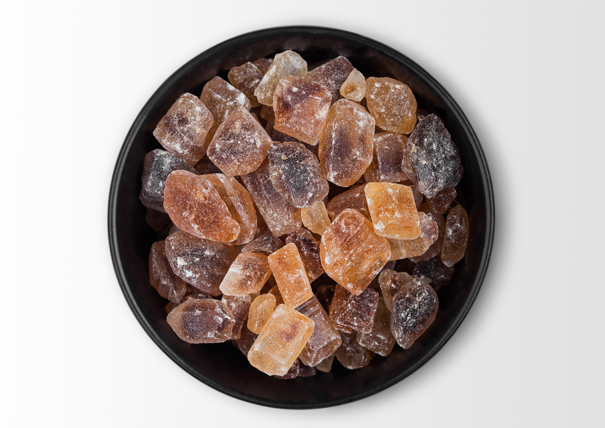 black bowl of natural brown caramelized sugar cubes on white bac