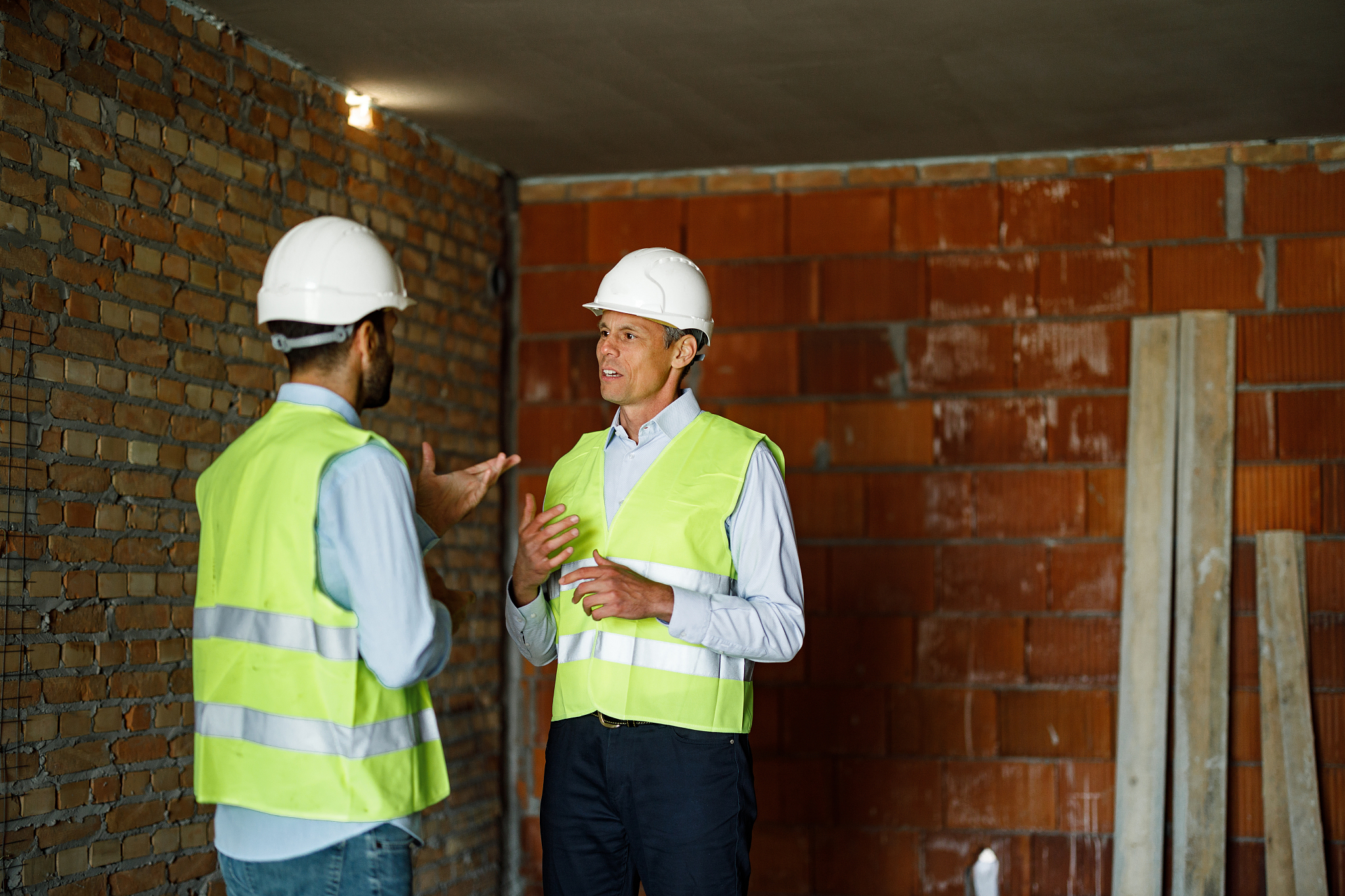 mid adult building contractors talking at construction site.