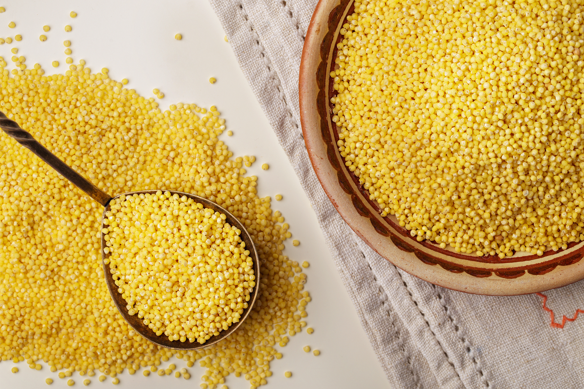 millet or foxtail grain on spoon and plate, close up, top view
