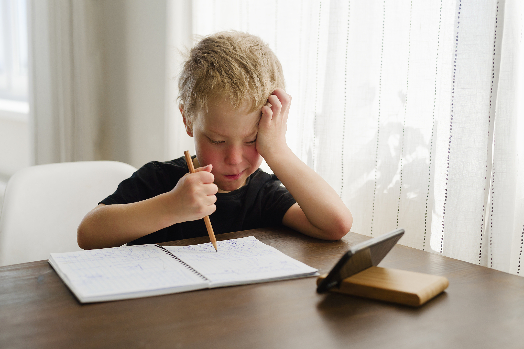 little boy learning at home and writing in notebook