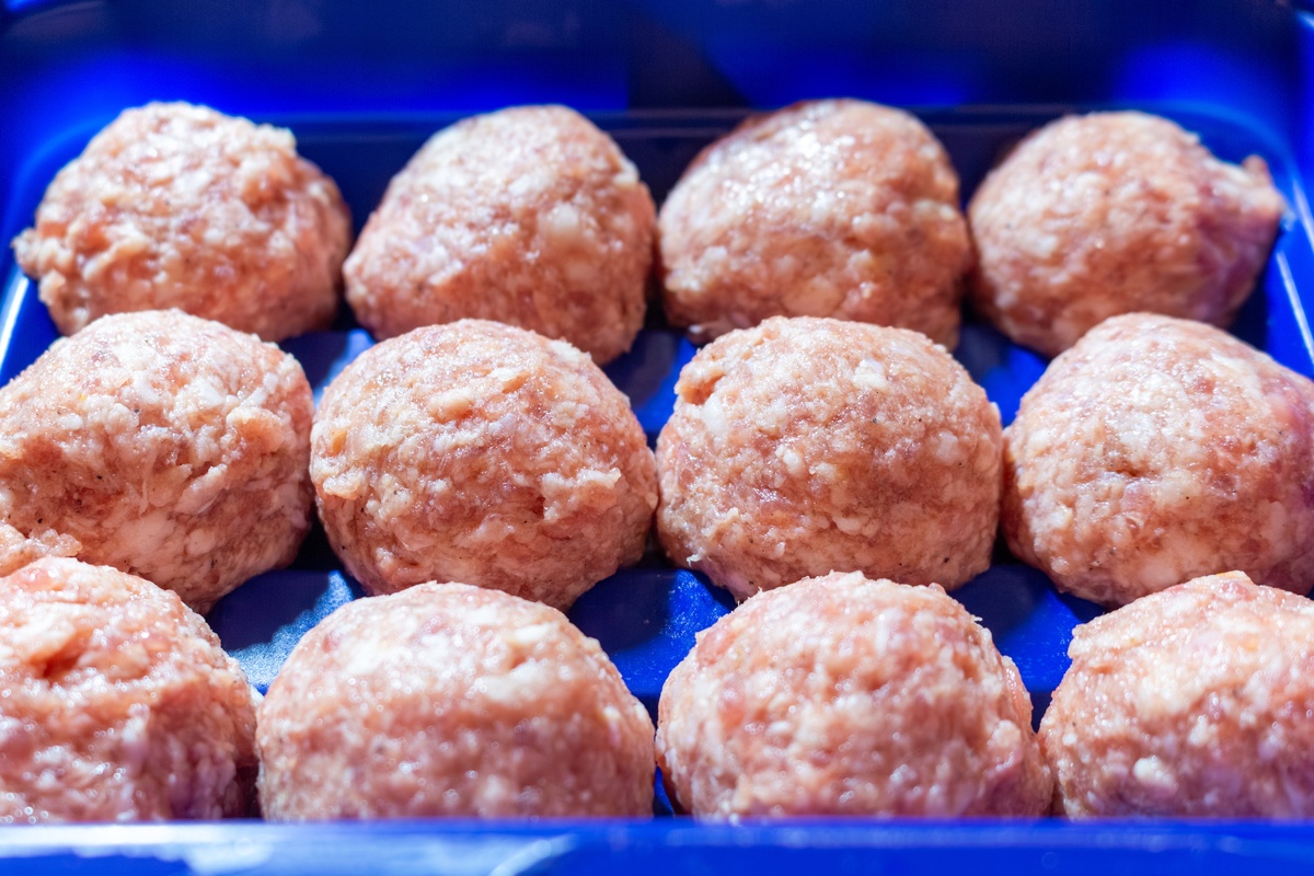 准备烹饪的蓝色塑料容器中的生肉<strong>丸</strong>,美味食物概念