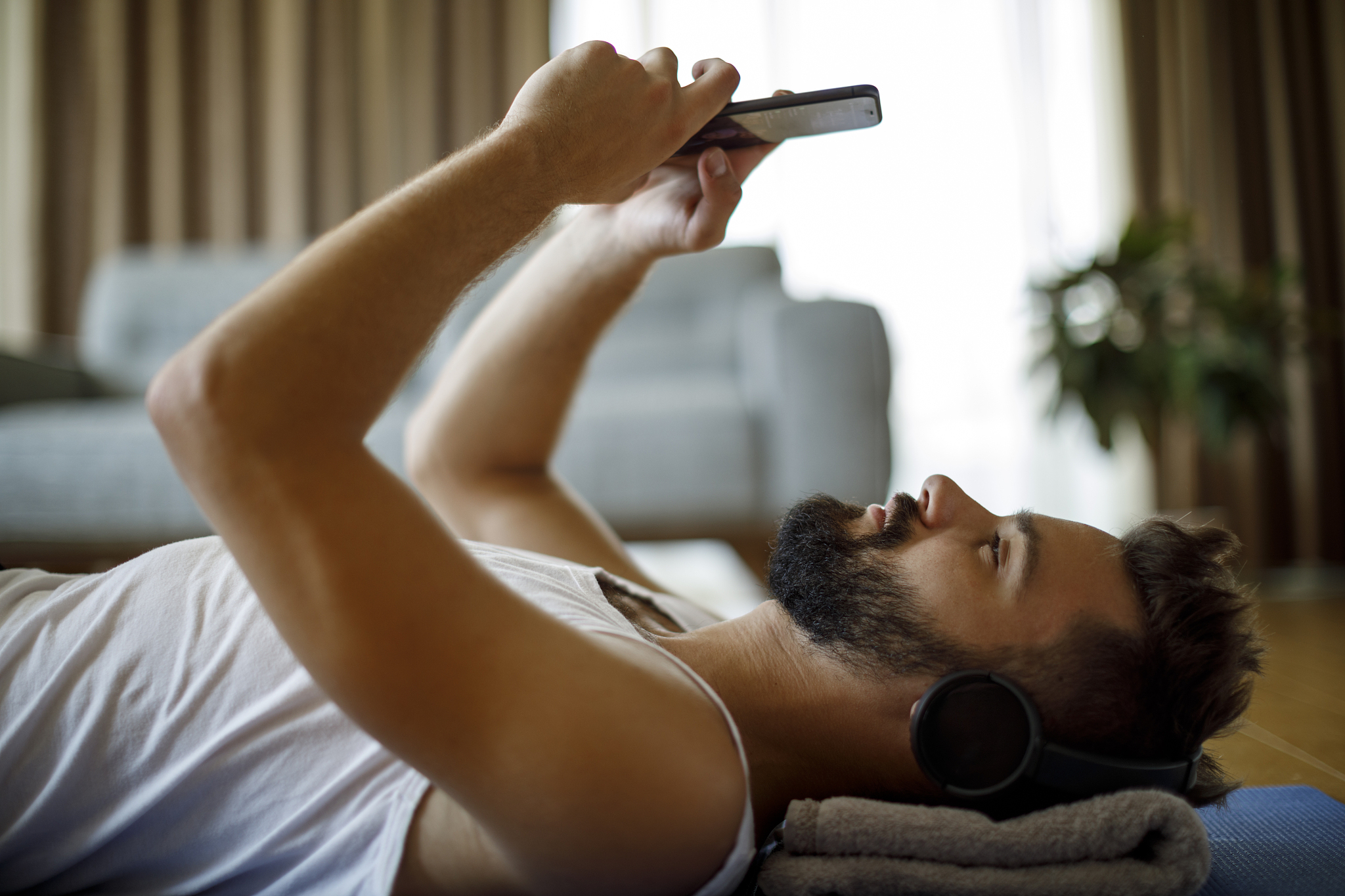 young smiling man with headphones and mobile phone relaxing afte