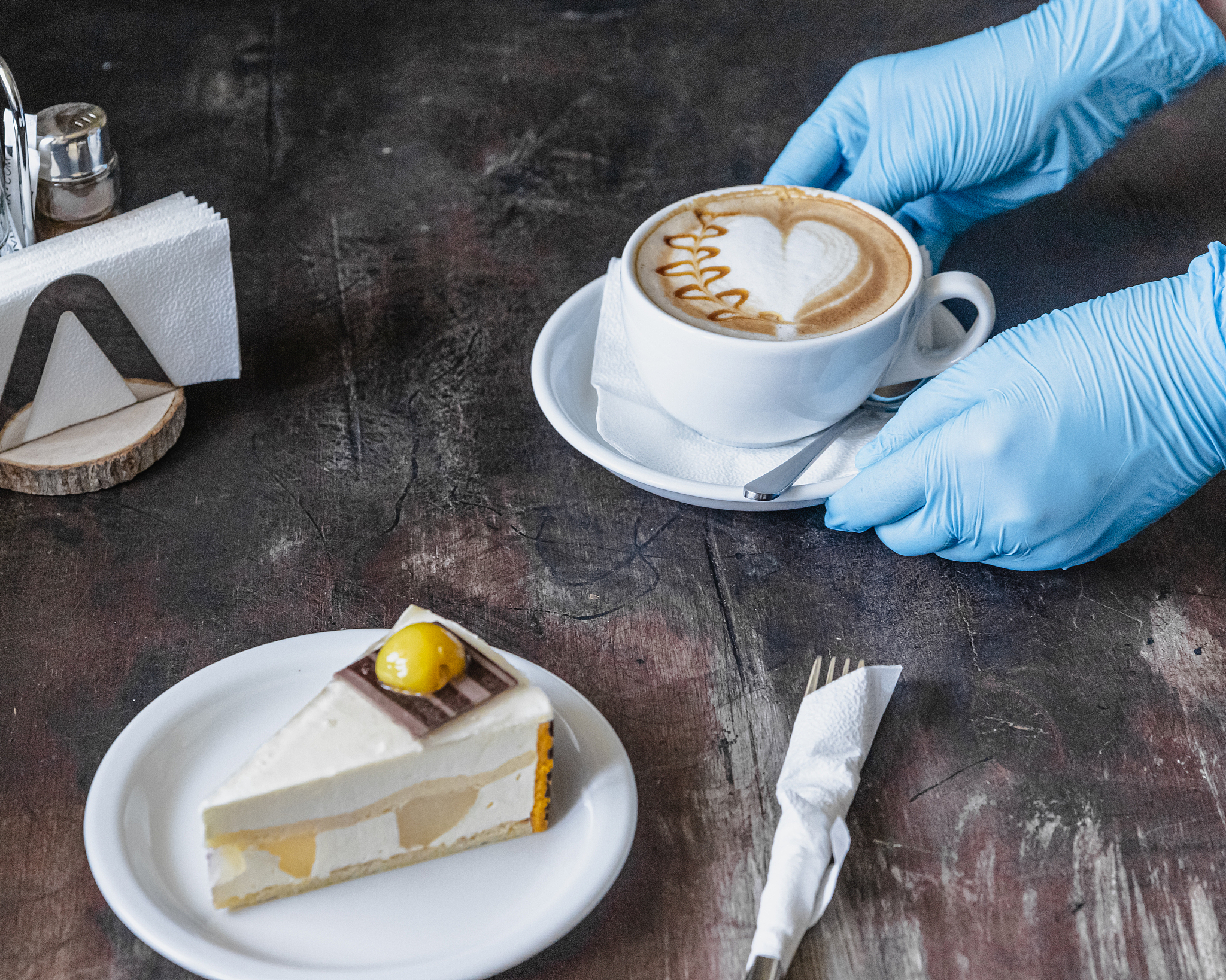 a waitress in medical gloves serves coffee in a coffee shop afte