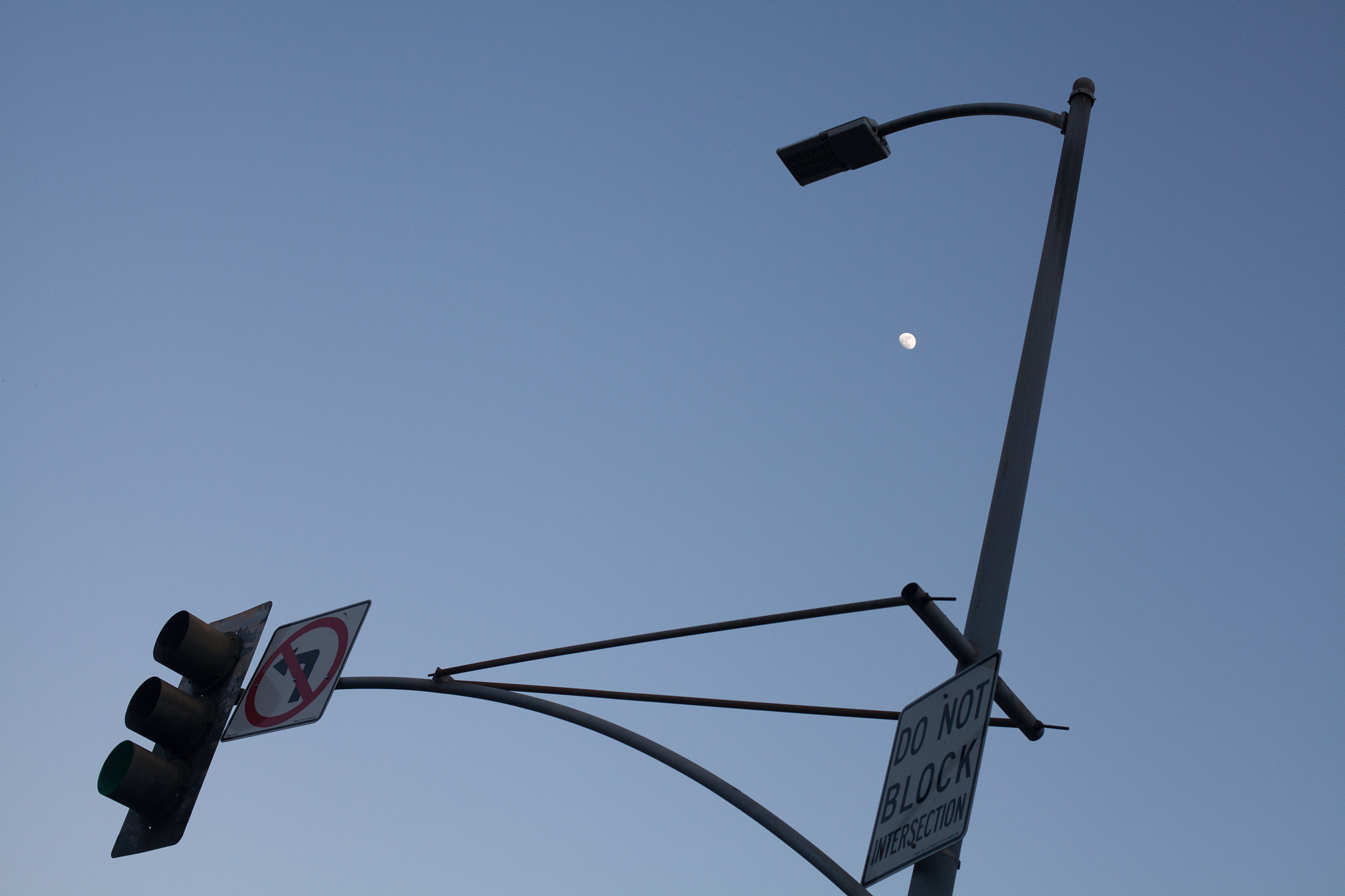 low angle view of road sign with street light against clear sky 