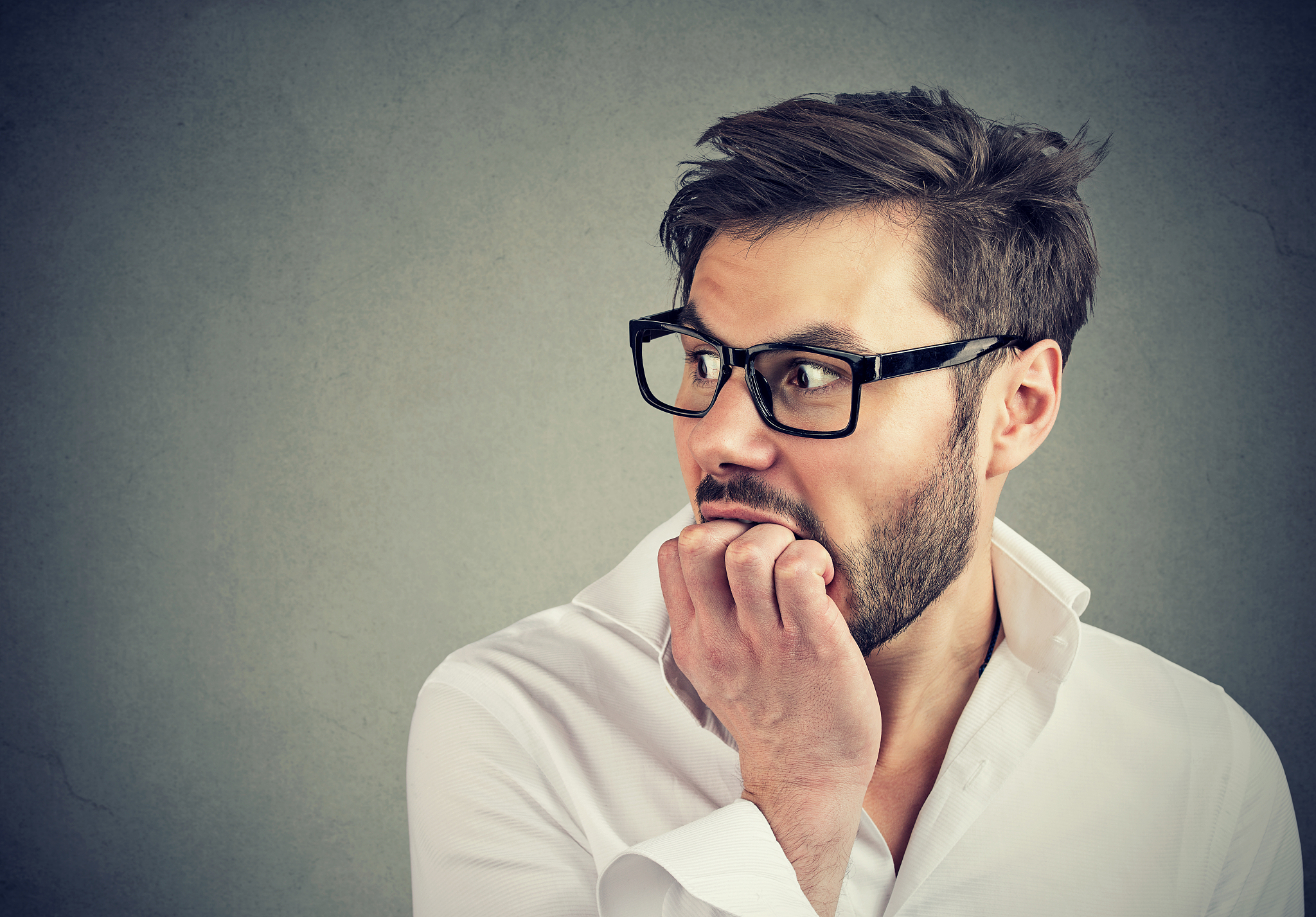 preoccupied anxious man biting his fingernails looking to the si