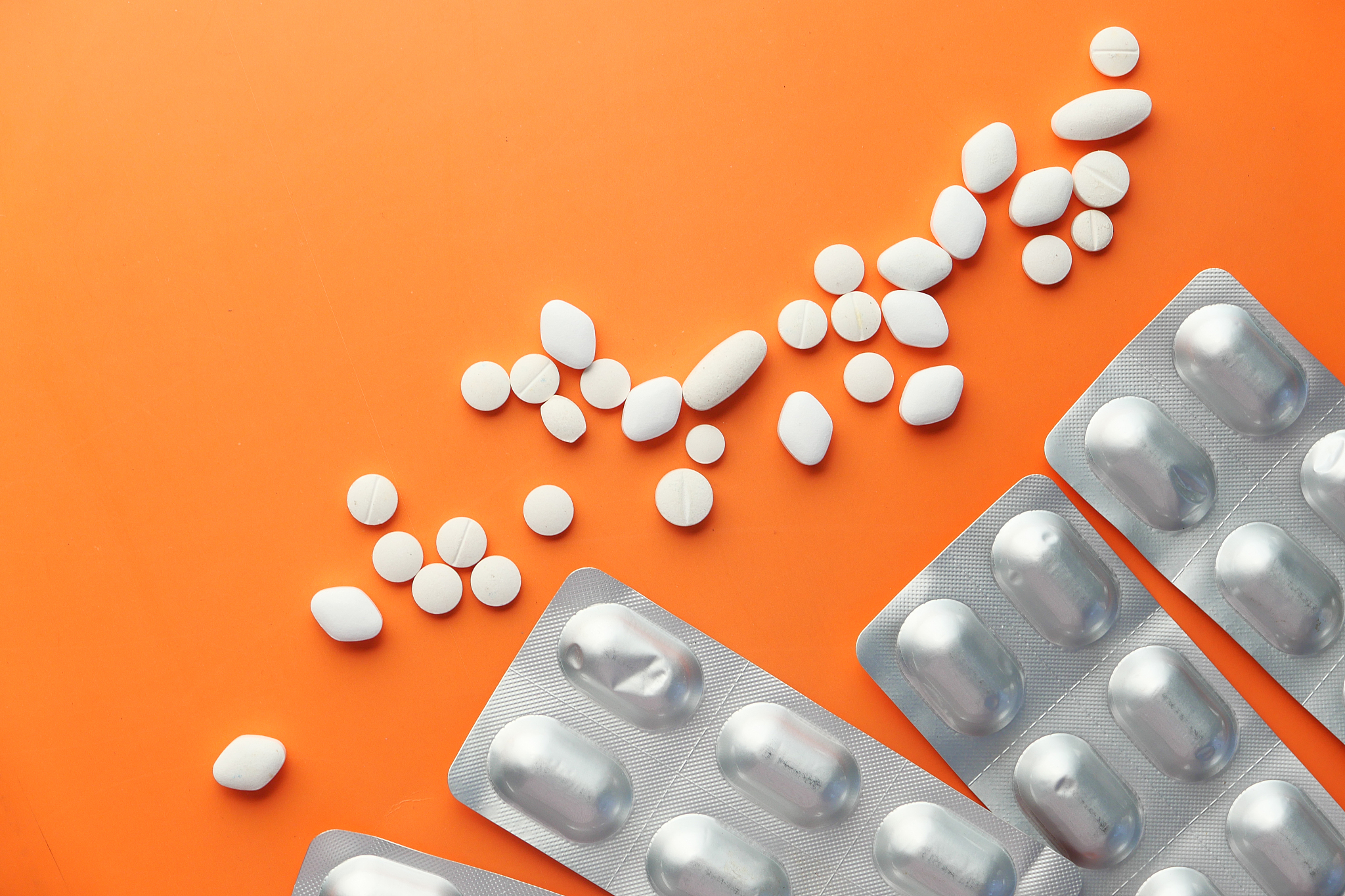 white pills and blister pack on orange background