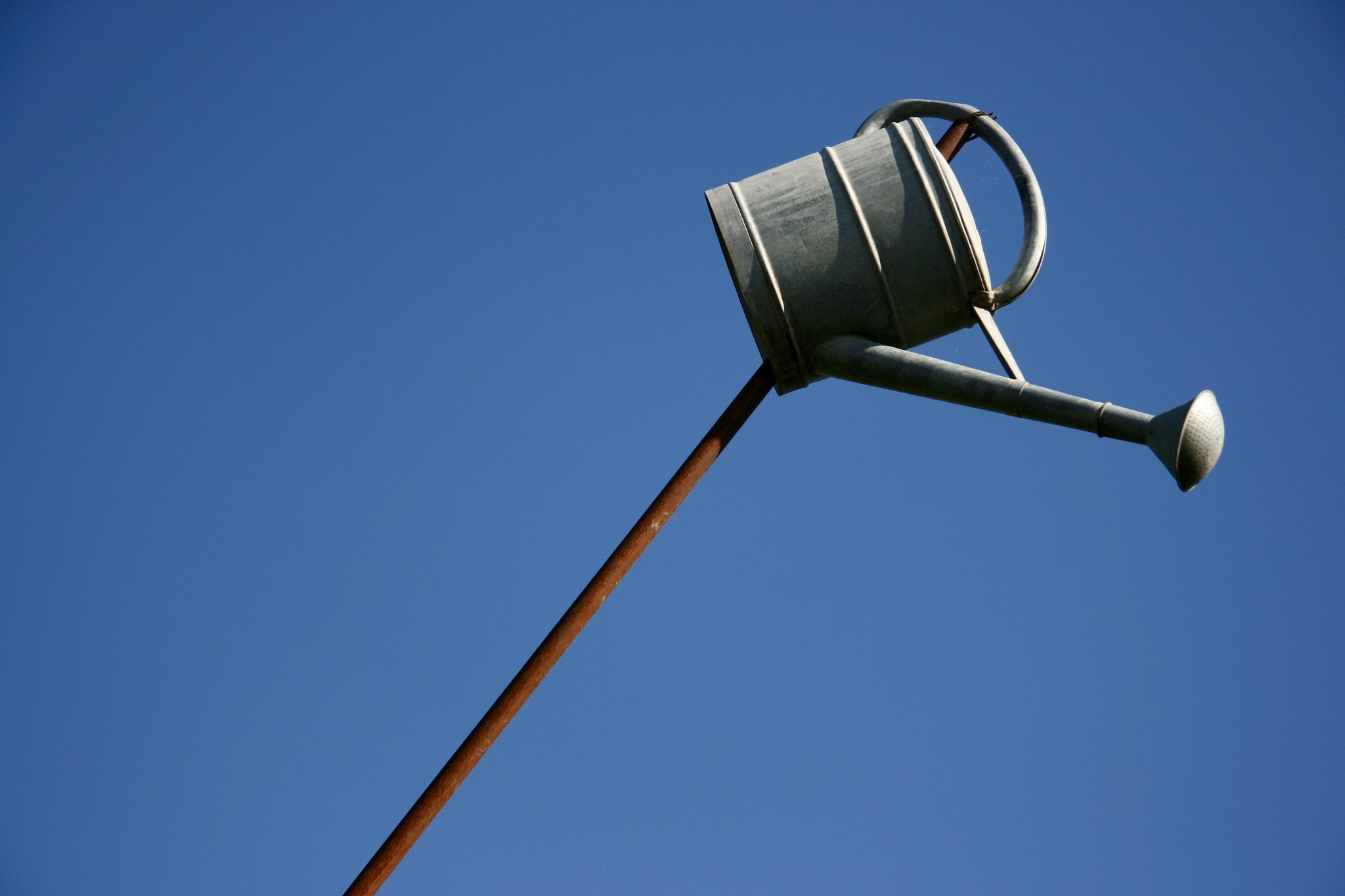 low angle view of watering can on pole against clear blue sky