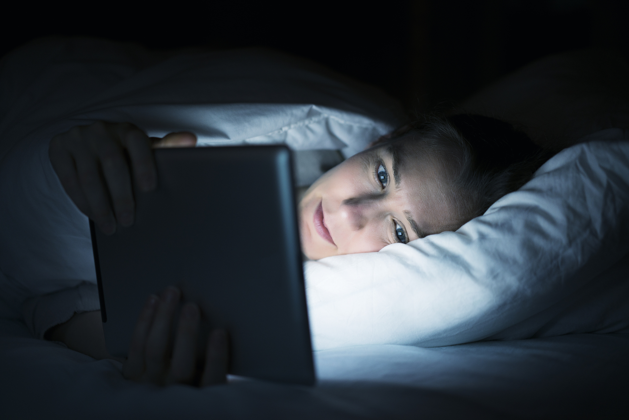 woman using tablet pc in bed at night