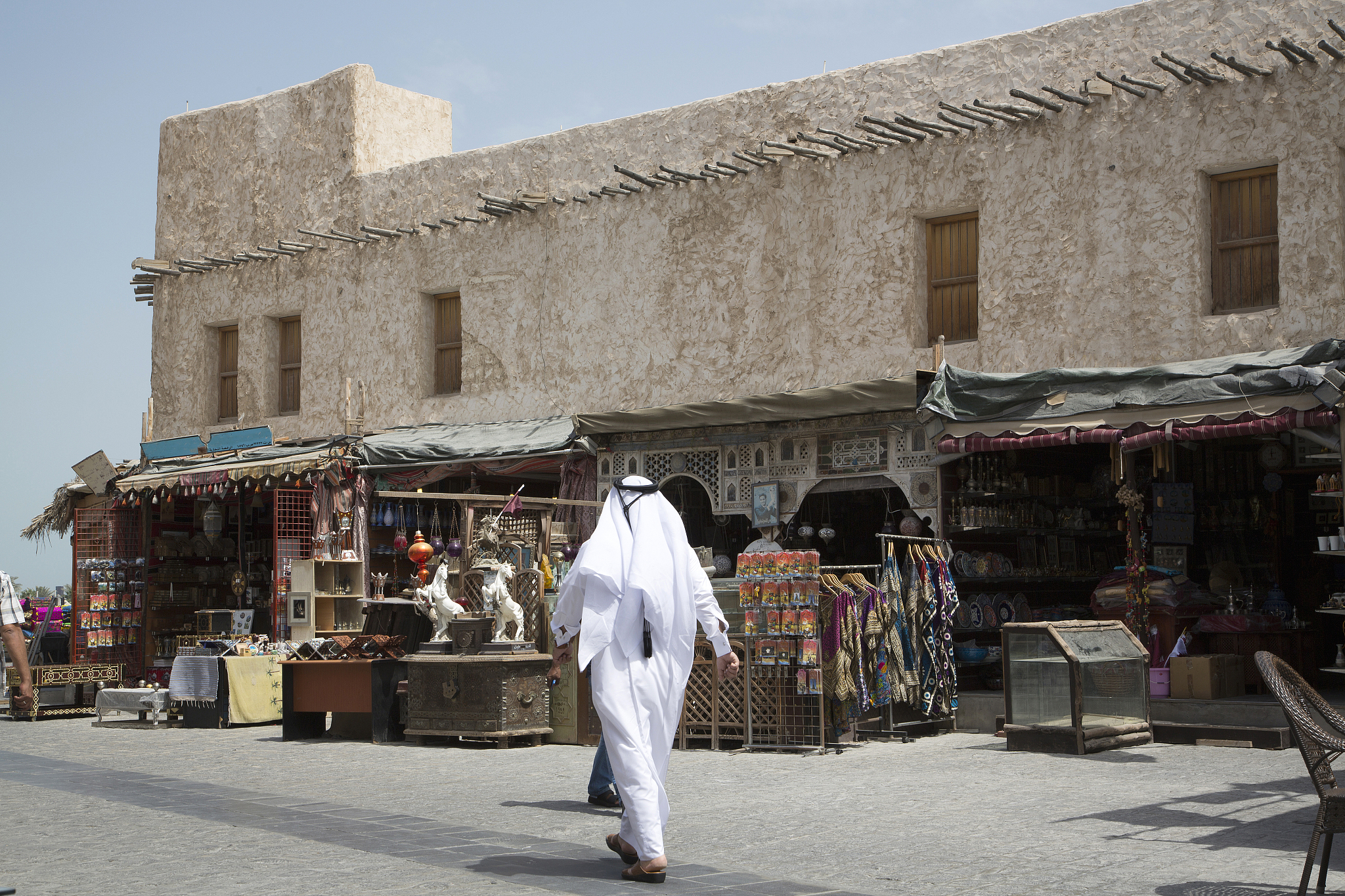 man walking outside market on doha sidewalk, doha, qatar