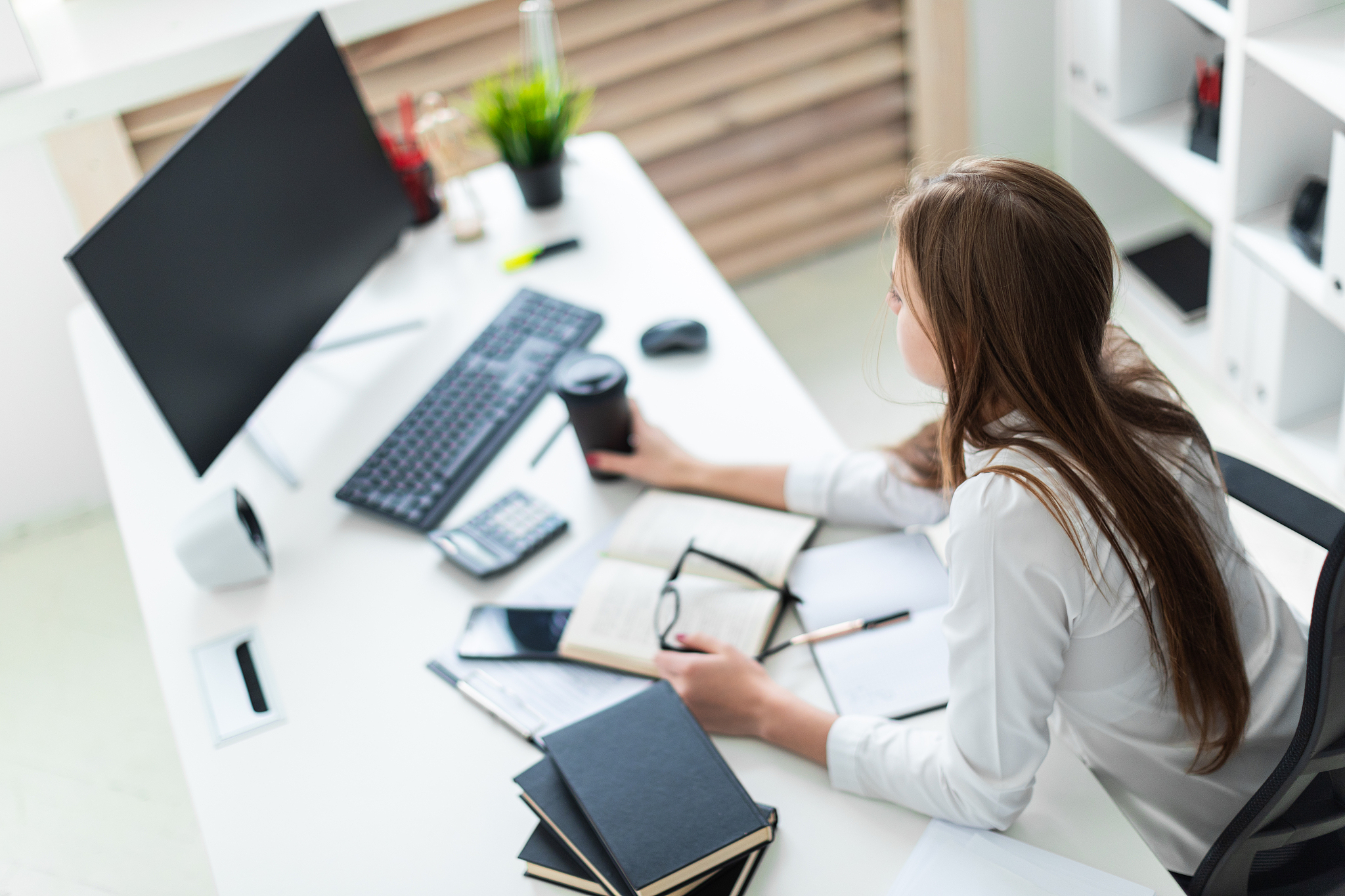 a young girl holding glasses and working in the office with book