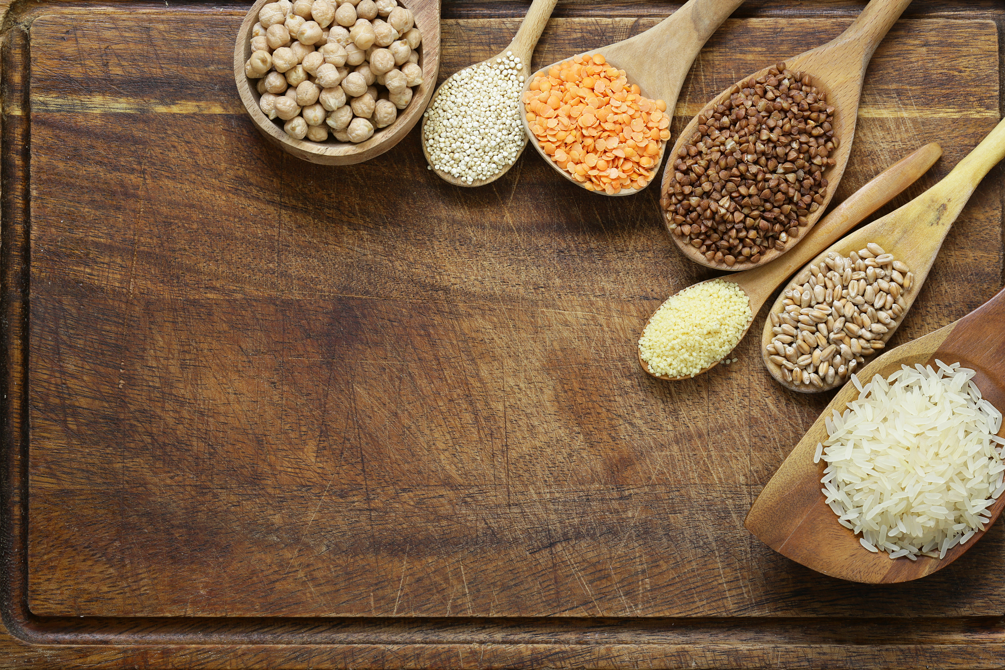 different types of cereals in wooden spoons - buckwheat, chickpe