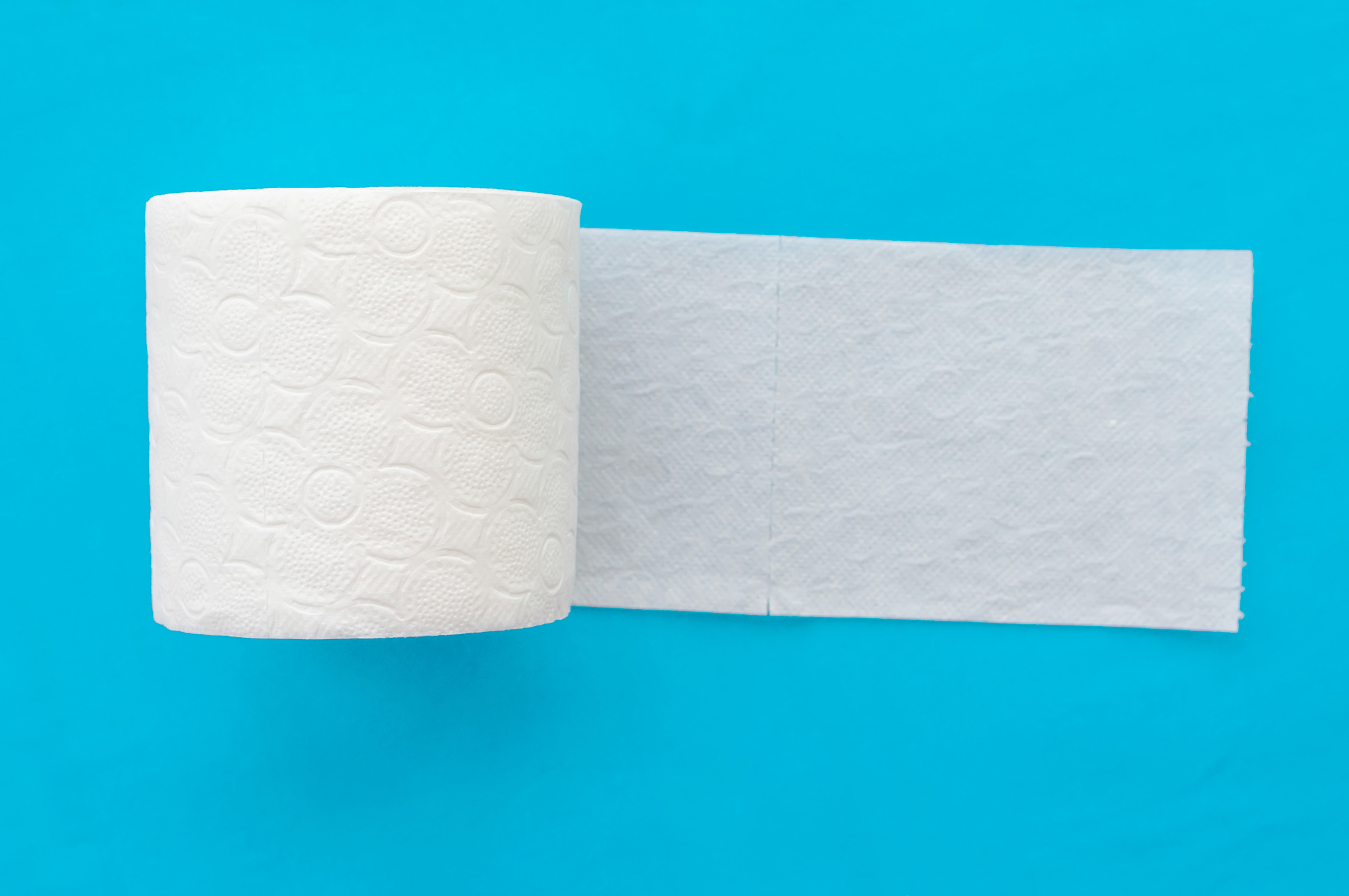 roll of white toilet paper on a blue background. close up.