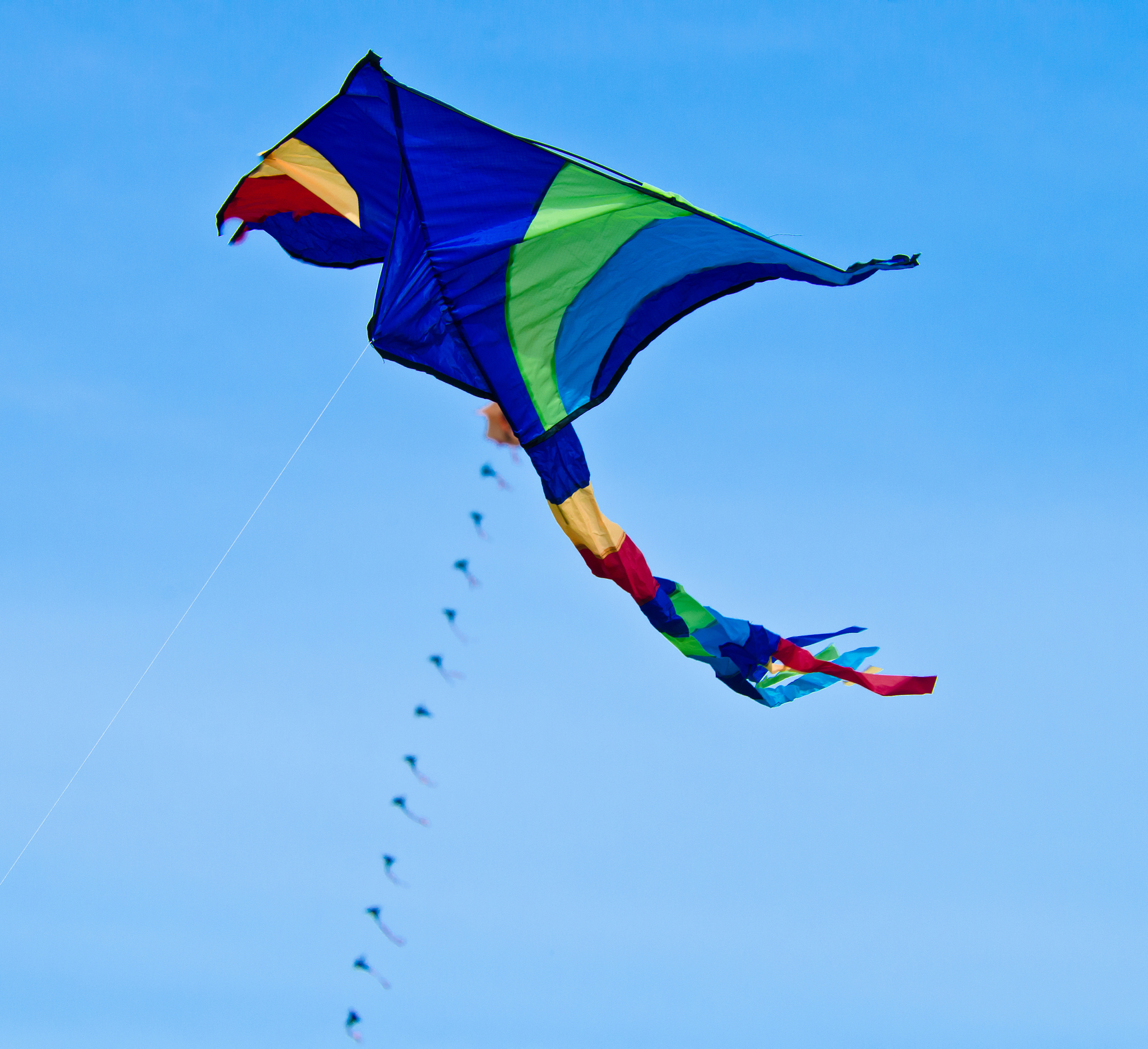 a beautiful, colourful stunt kite, in the blue sky, high up in t