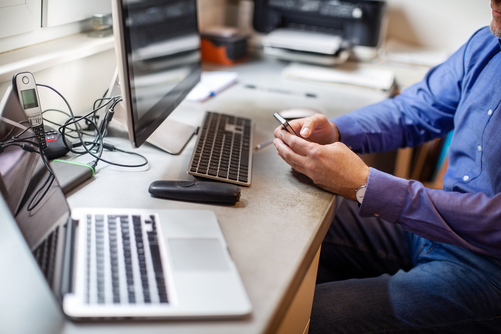 male owner using phone over workbench in workshop