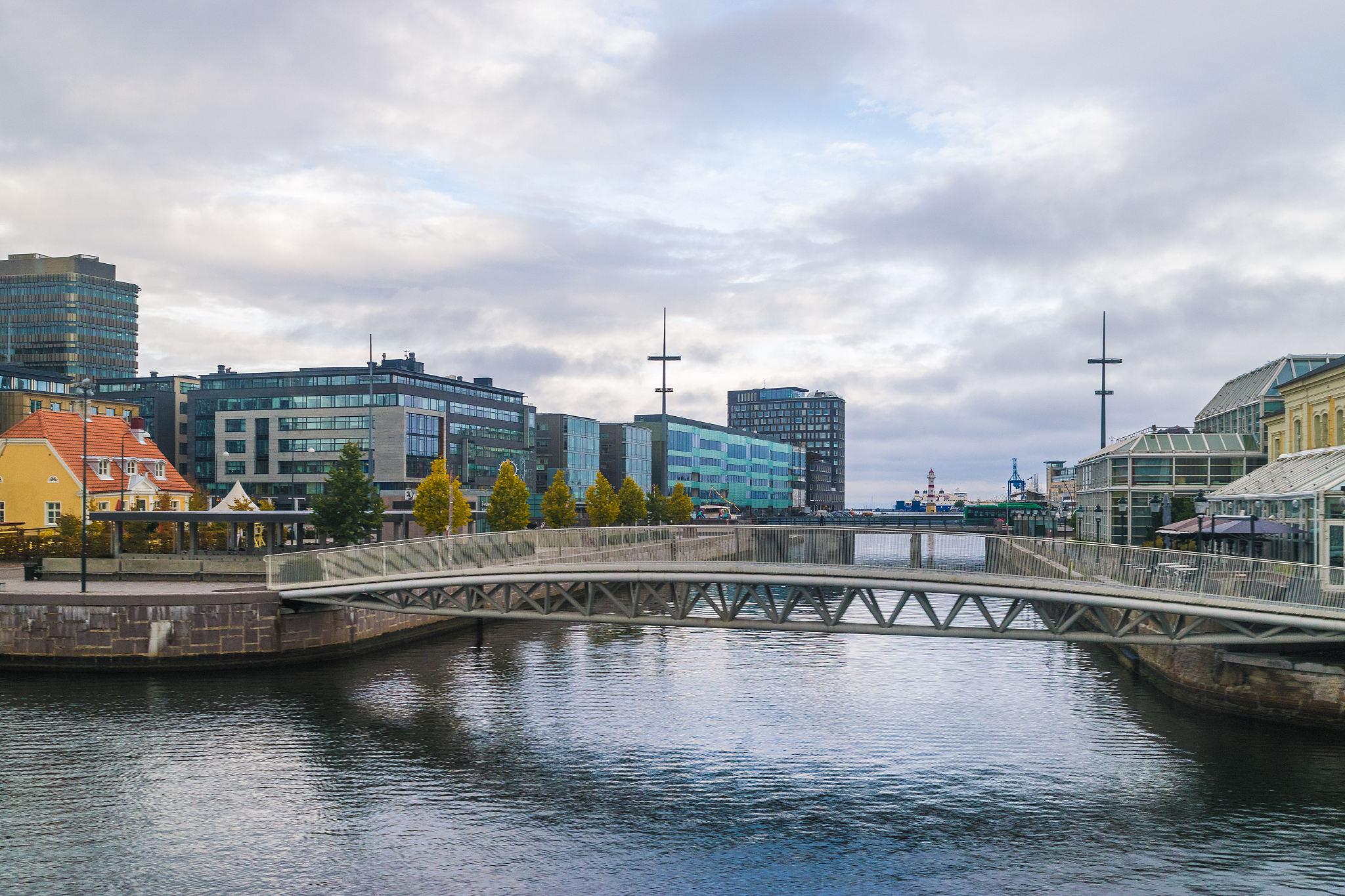 bridge over river by buildings in city against sky