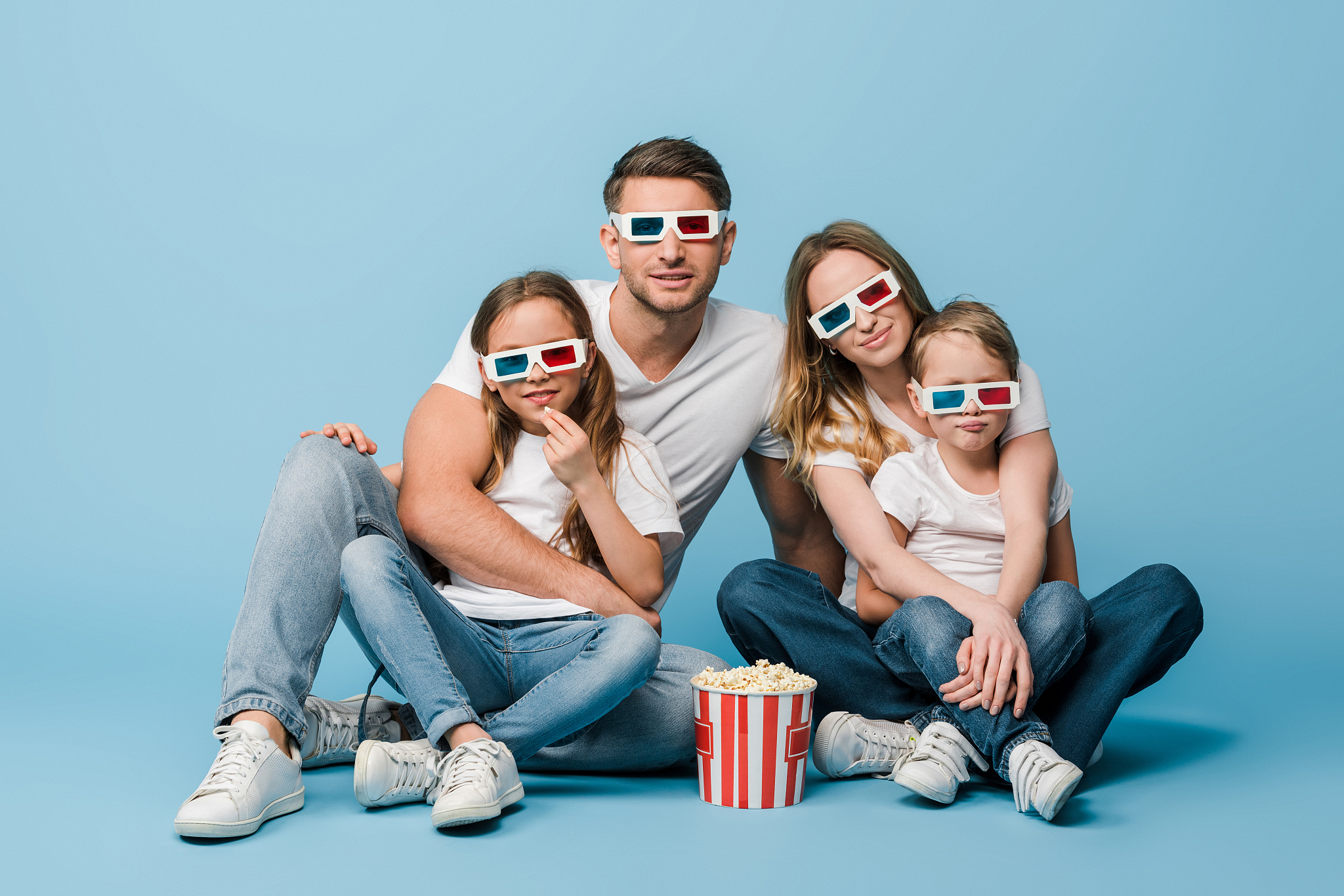 happy family watching movie in 3d glasses with popcorn bucket on
