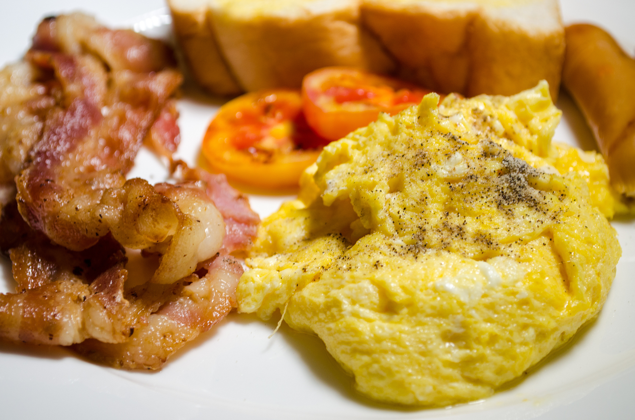 breakfast with scrambled eggs, toasts,bacon and sausage.
