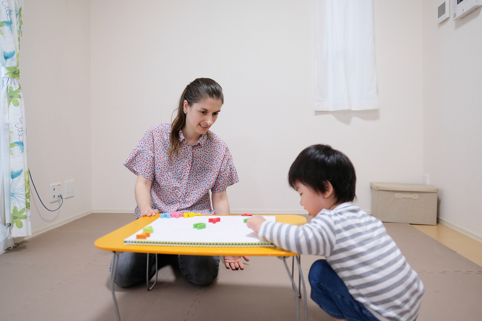 caucasian woman teaching english to asian toddler with alphabet 
