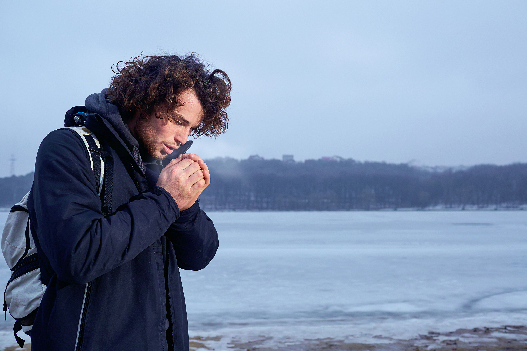 the concept of cold, frost. curly haired young man warming his