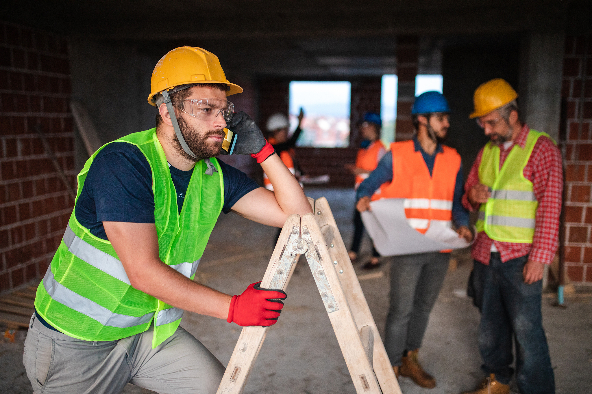 handsome handyman making a phone call at construction site