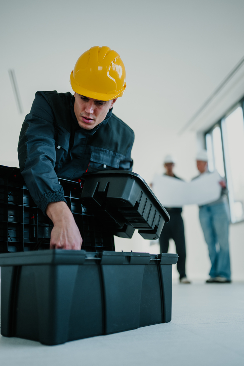 建筑工人在施工现场的工具箱中挑选工具,团队成员正在